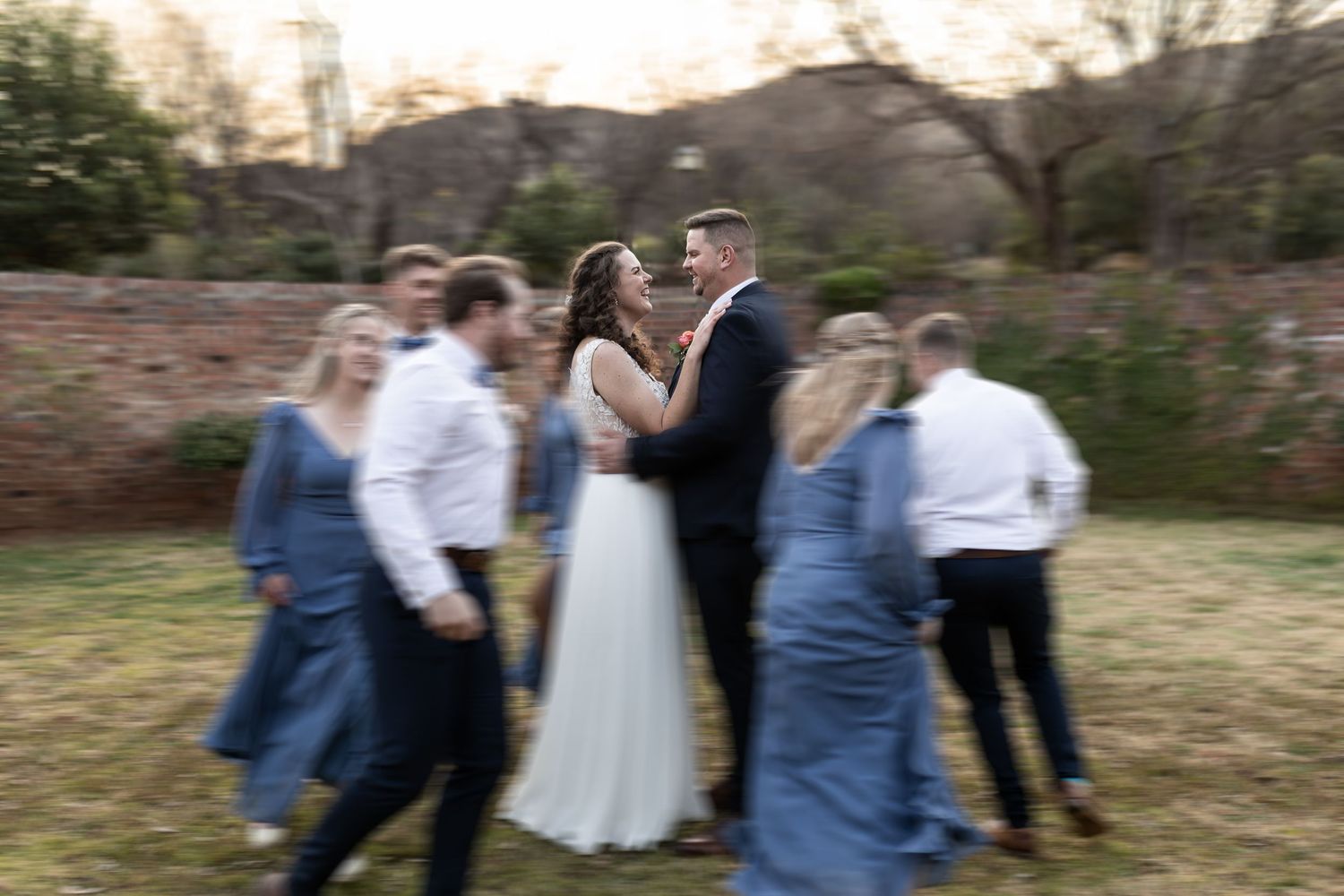 Group of people dancing and celebrating outdoors at a rustic outdoor event or celebration.