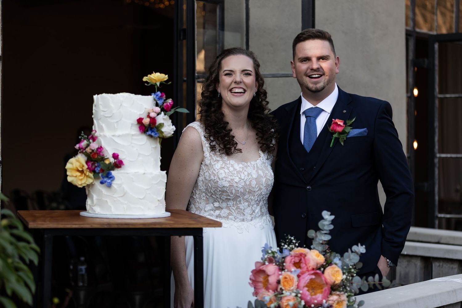 Collage of wedding photos featuring a tiered white cake decorated with colorful fresh flowers at a reception.