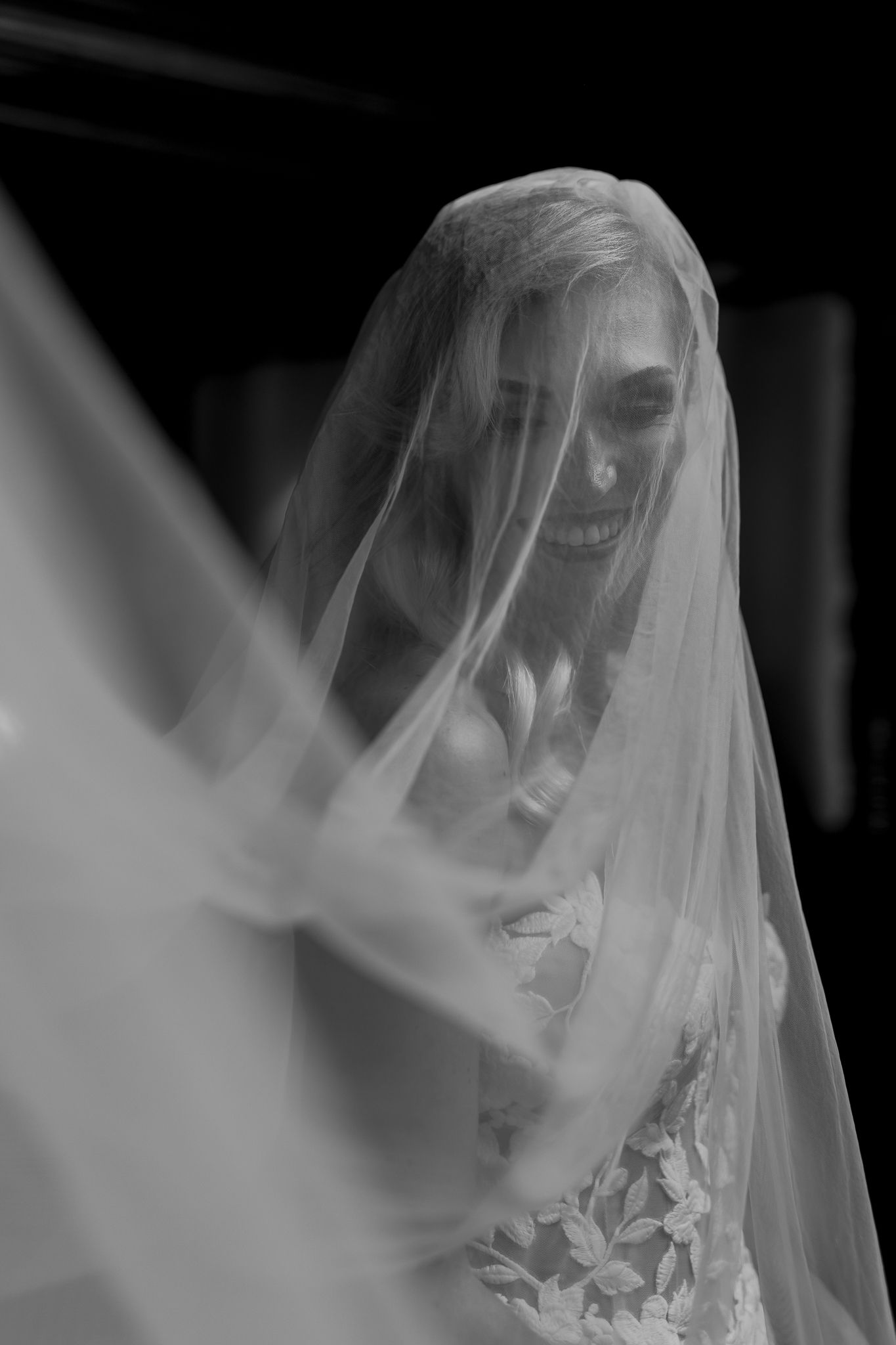 Black and white portrait of bride with flowing veil in soft natural light.