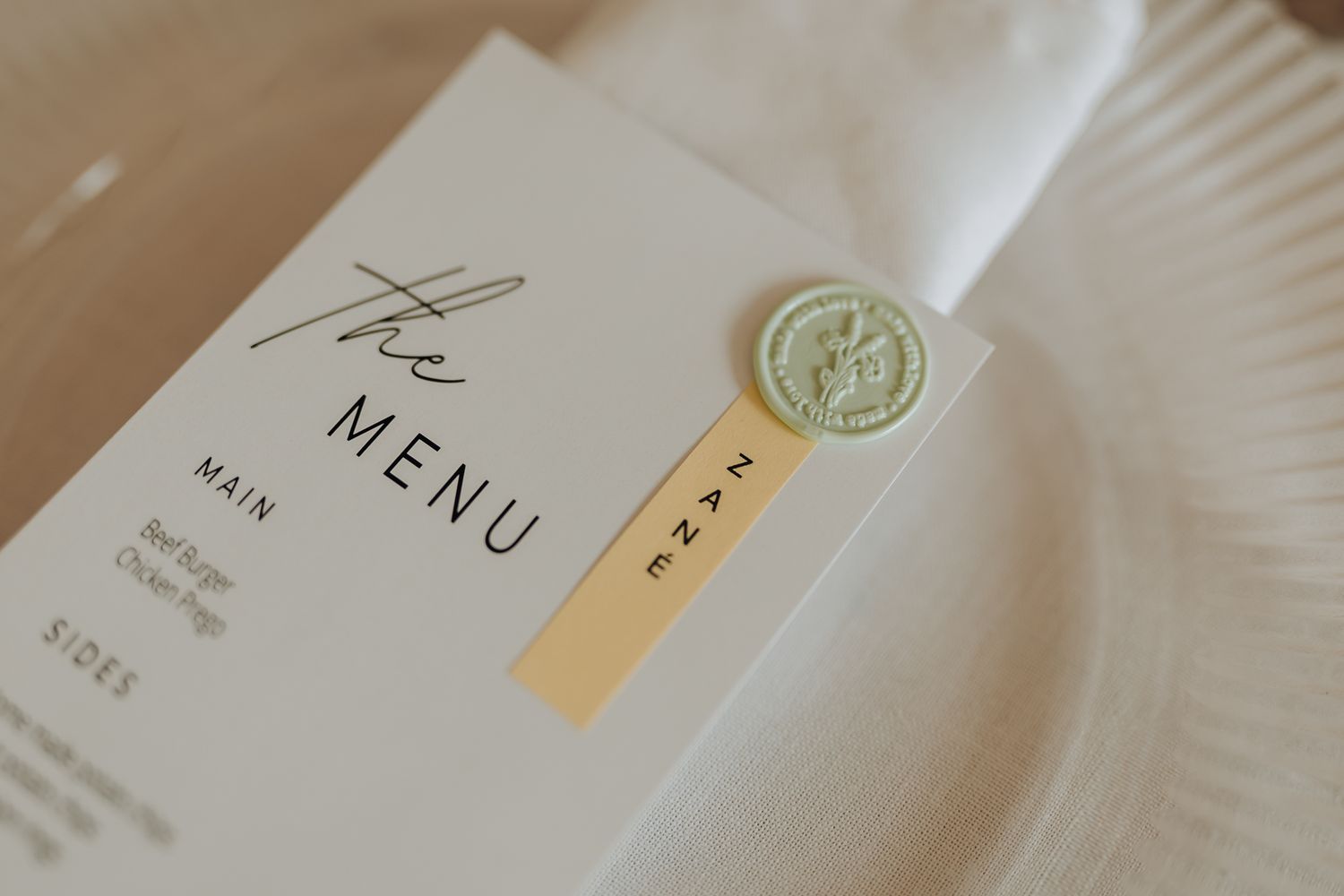 Close-up of an elegant wedding menu card featuring a gold wax seal and modern typography.