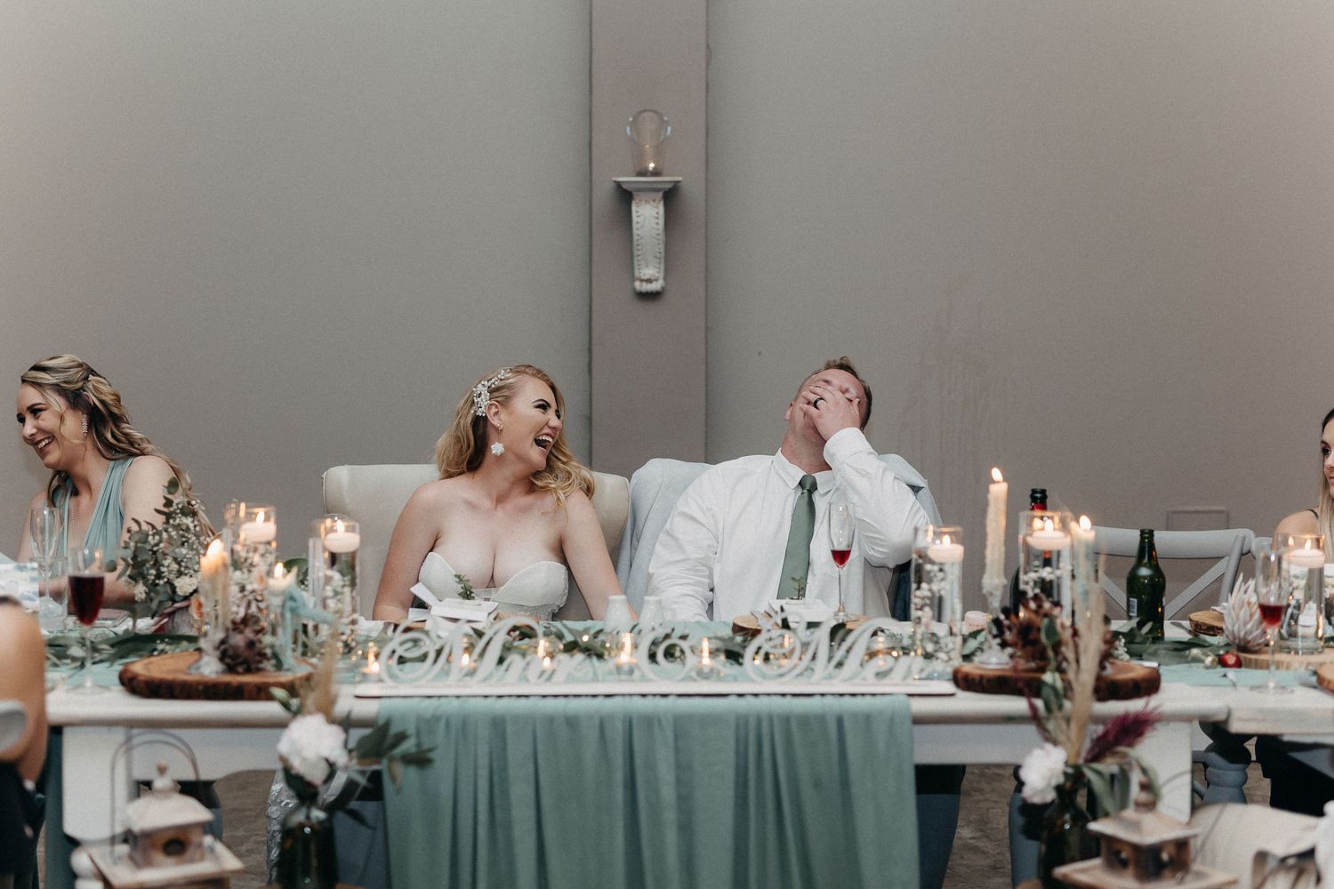 Joyful moment captured at wedding reception head table with elegant decor.