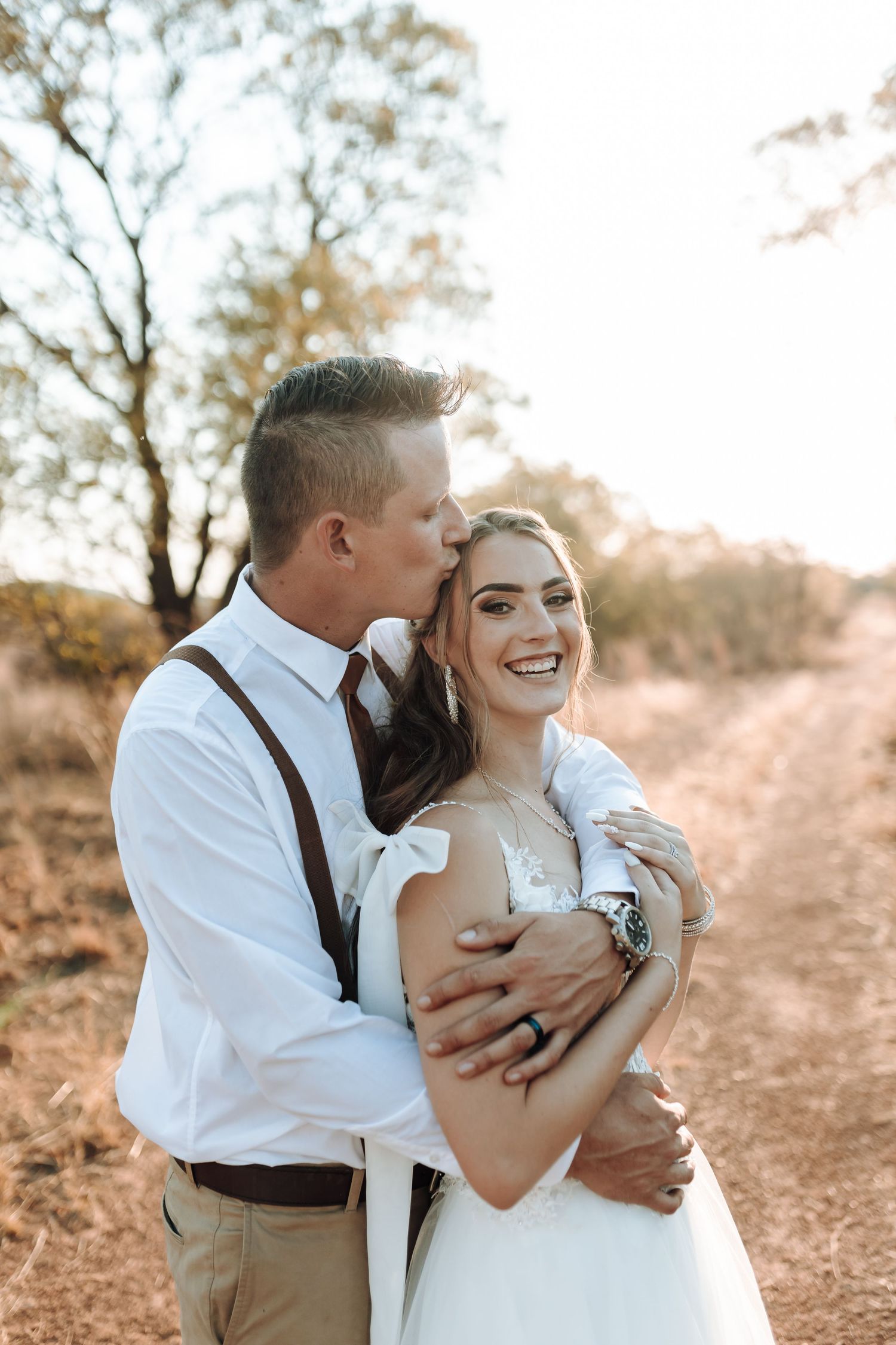 Joyful wedding couple sharing a loving moment on outdoor trail.