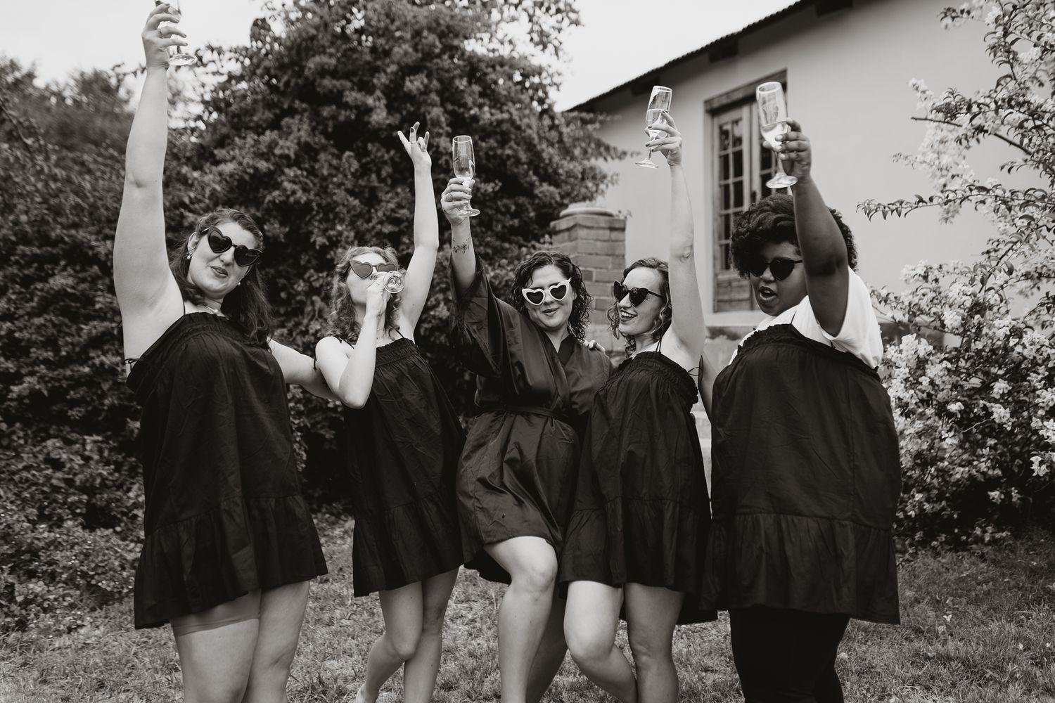 Celebratory black and white photo of group jumping in matching black outfits.