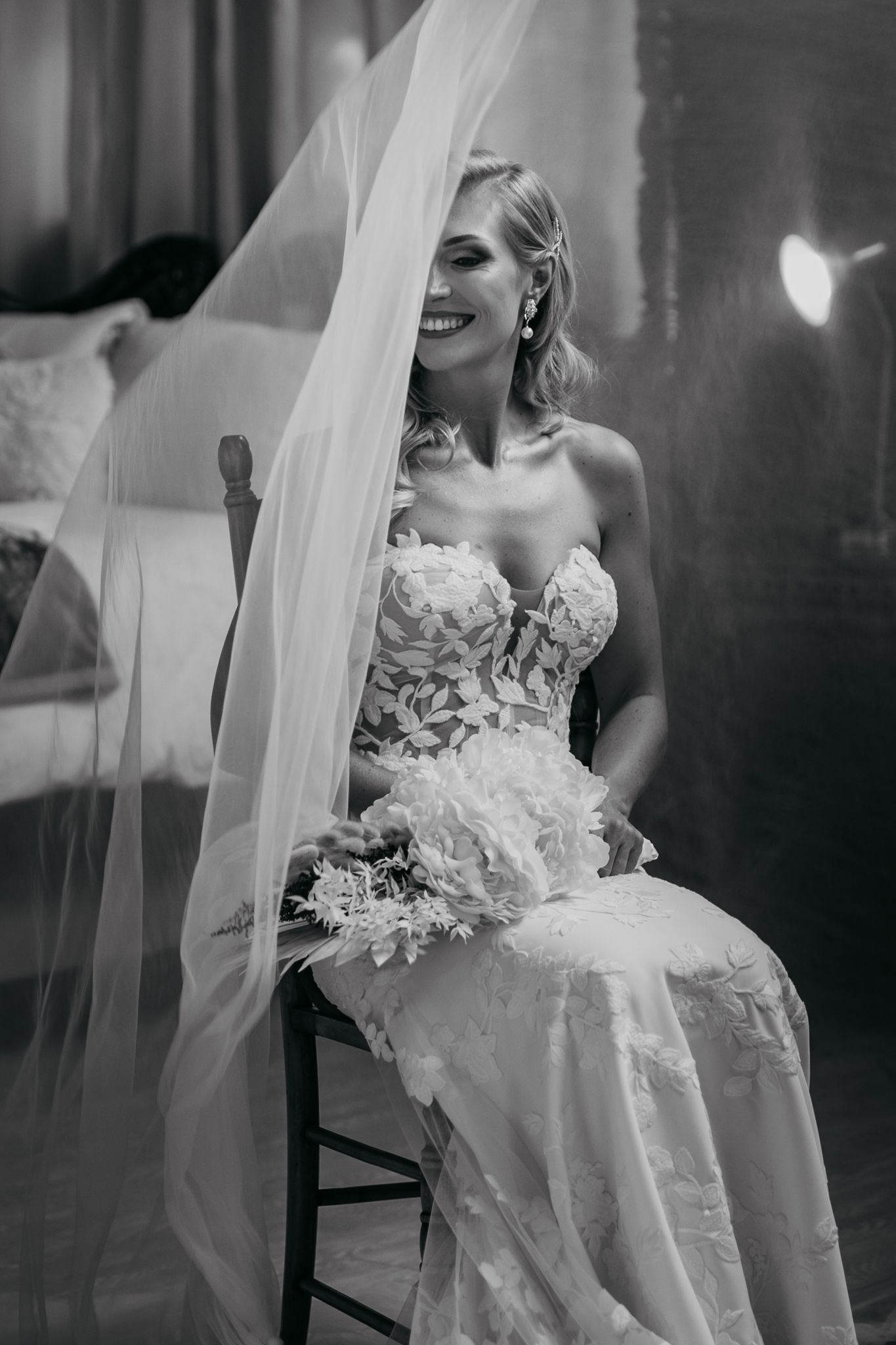 Classic black and white bridal portrait with flowing veil and intricate lace dress.