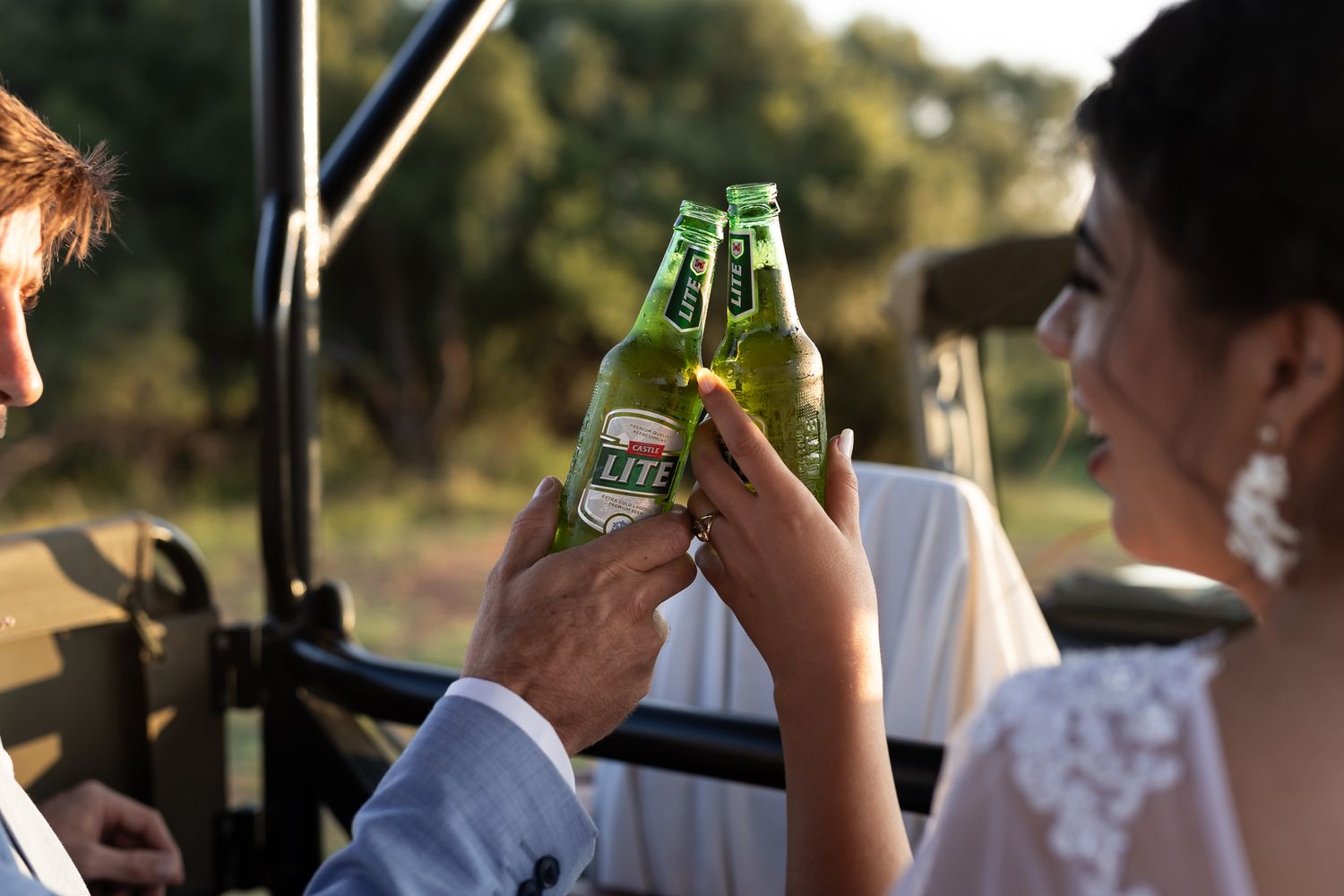 Newlyweds toasting with beer bottles in a celebratory moment during their wedding day.