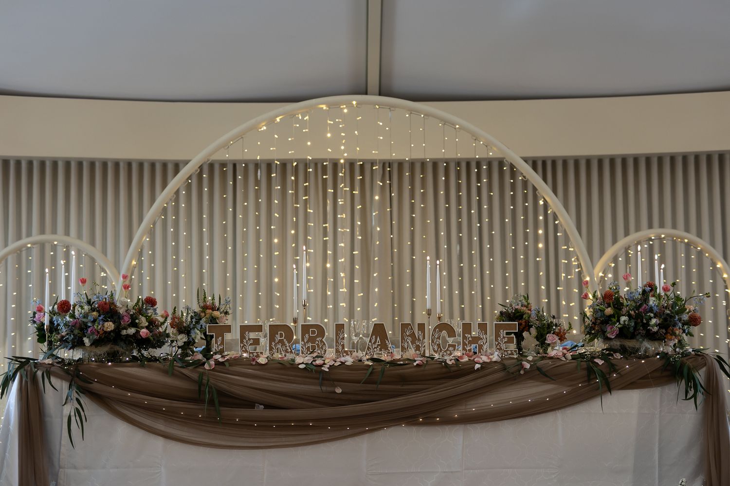 Wedding arch decorated with draped fabric and cascading crystal lights creating a magical backdrop.
