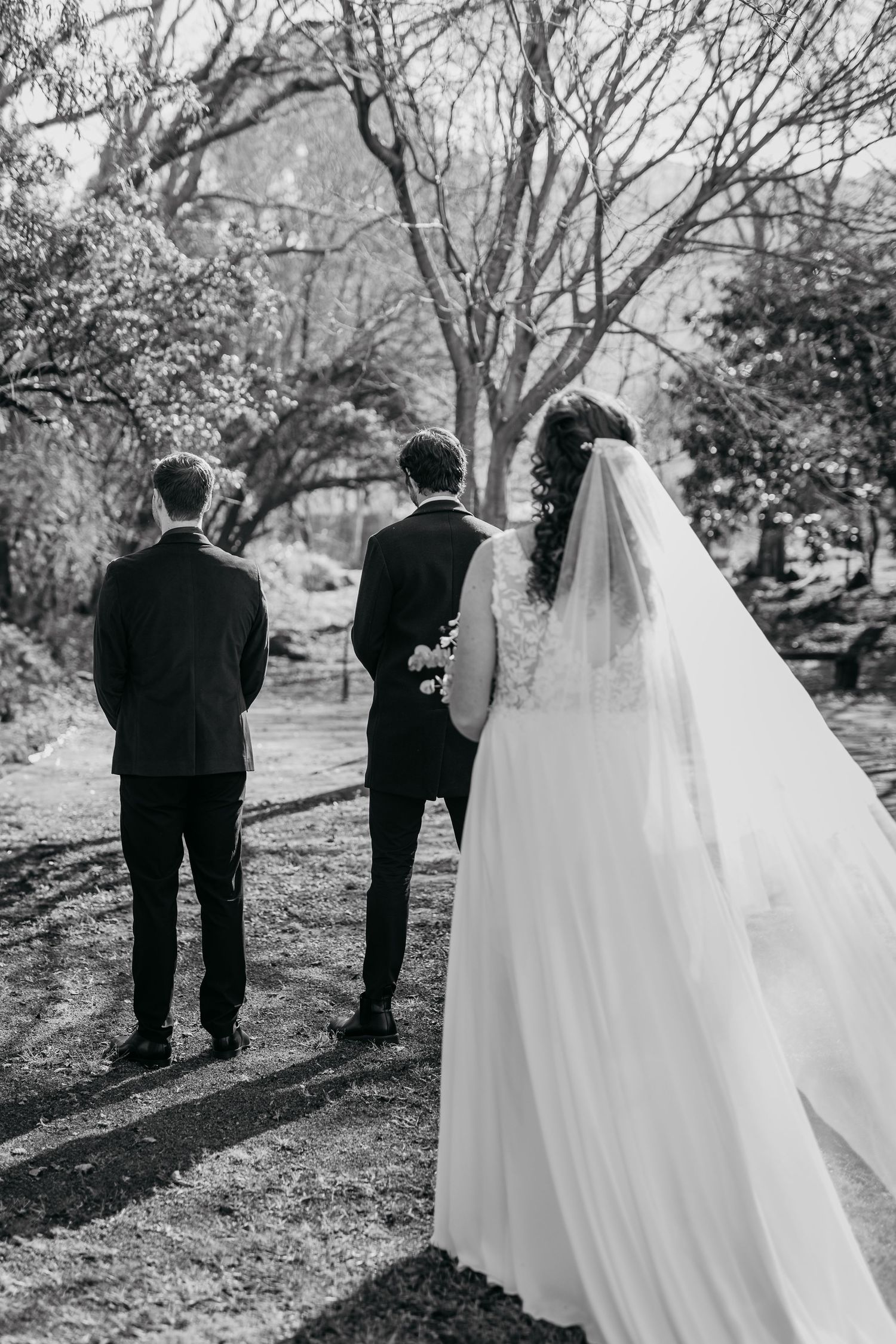 A black and white photo sequence shows a couple walking through a park together with a flowing white wedding dress.
