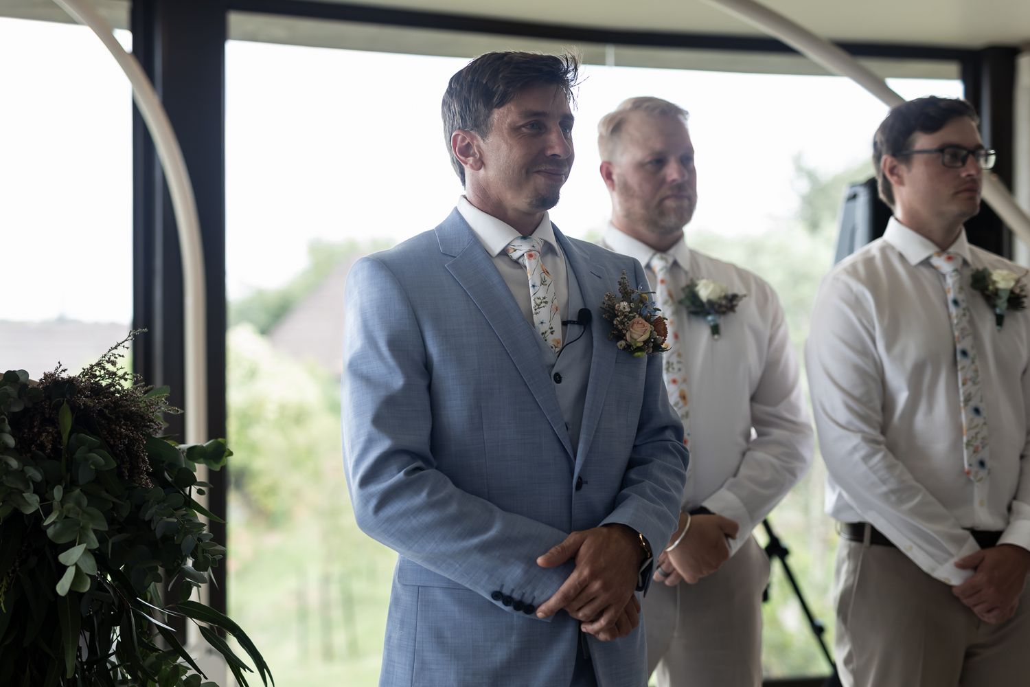 Groomsmen in formal attire stand at attention during wedding ceremony.