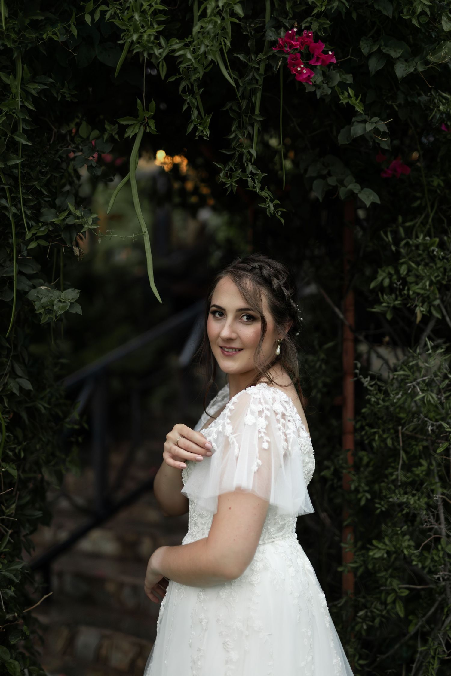 White lace wedding dress with short sleeves photographed in garden with red flowers.