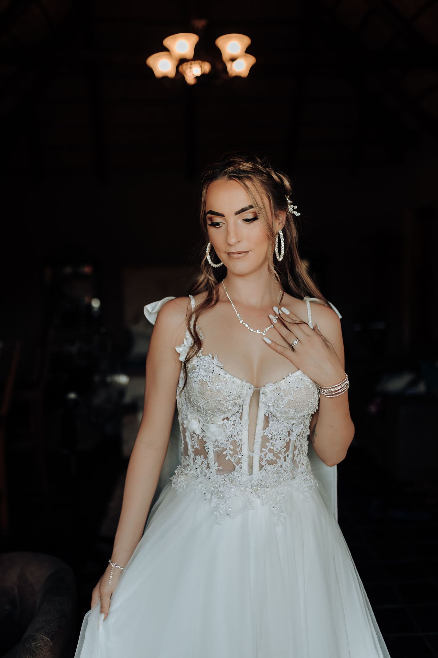 Elegant white wedding gown with lace bodice and tulle skirt in dramatic lighting.