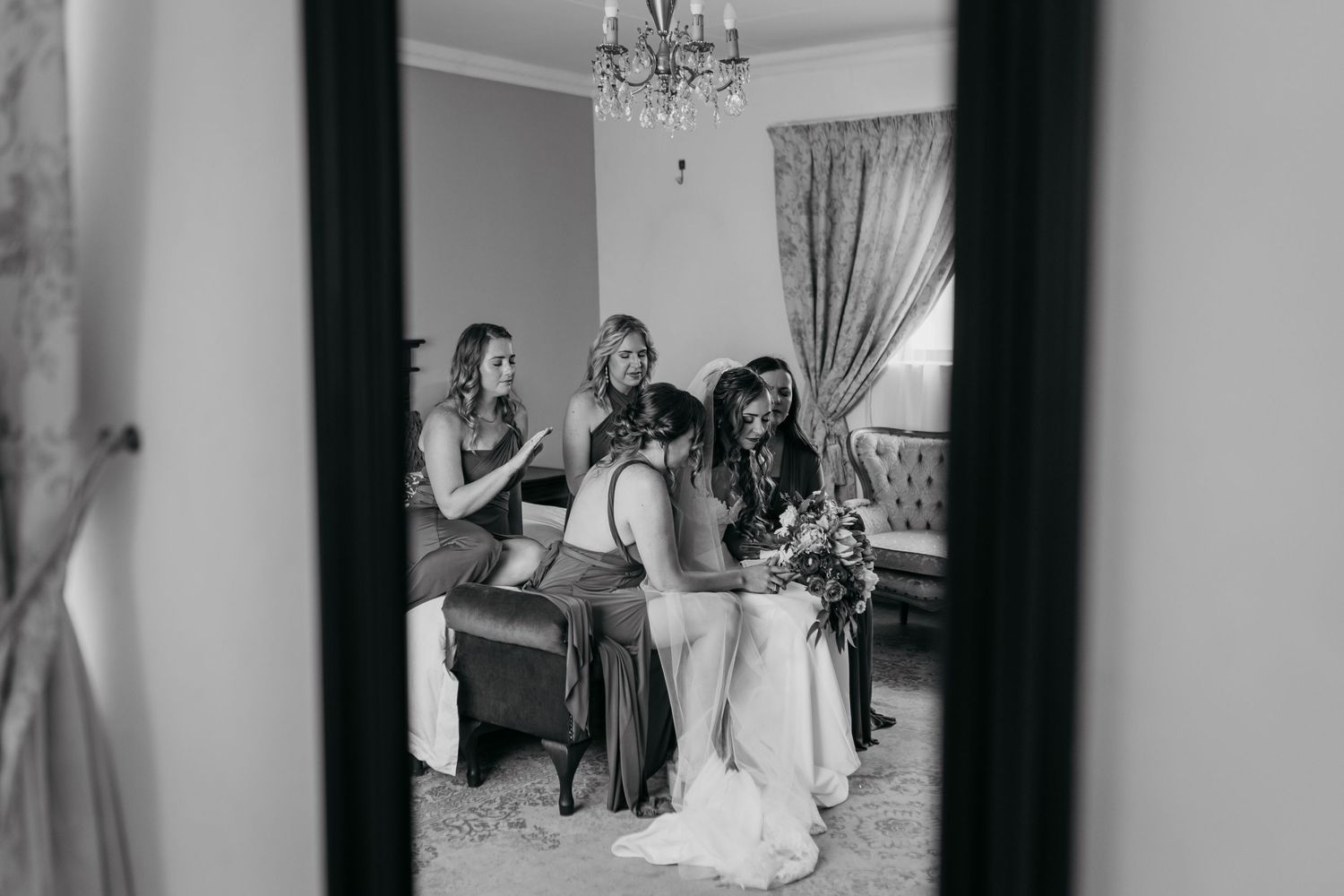 Black and white view through doorway of wedding preparations in elegant bedroom.
