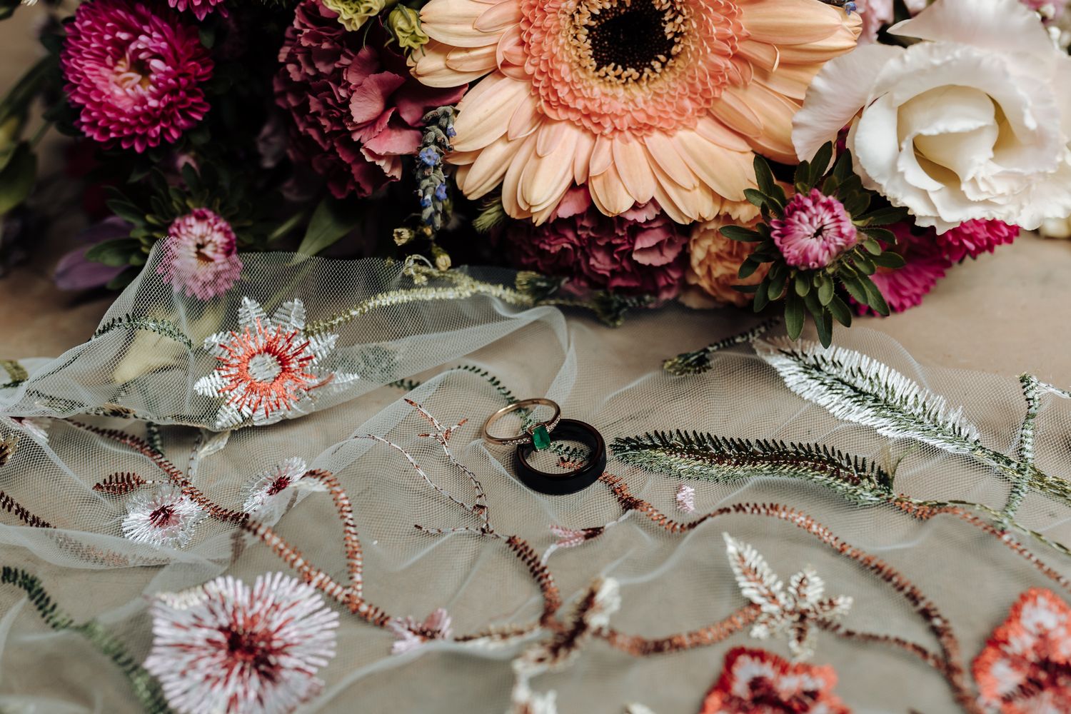 Wedding details featuring pink and peach flowers with delicate embroidered fabric and jewelry.