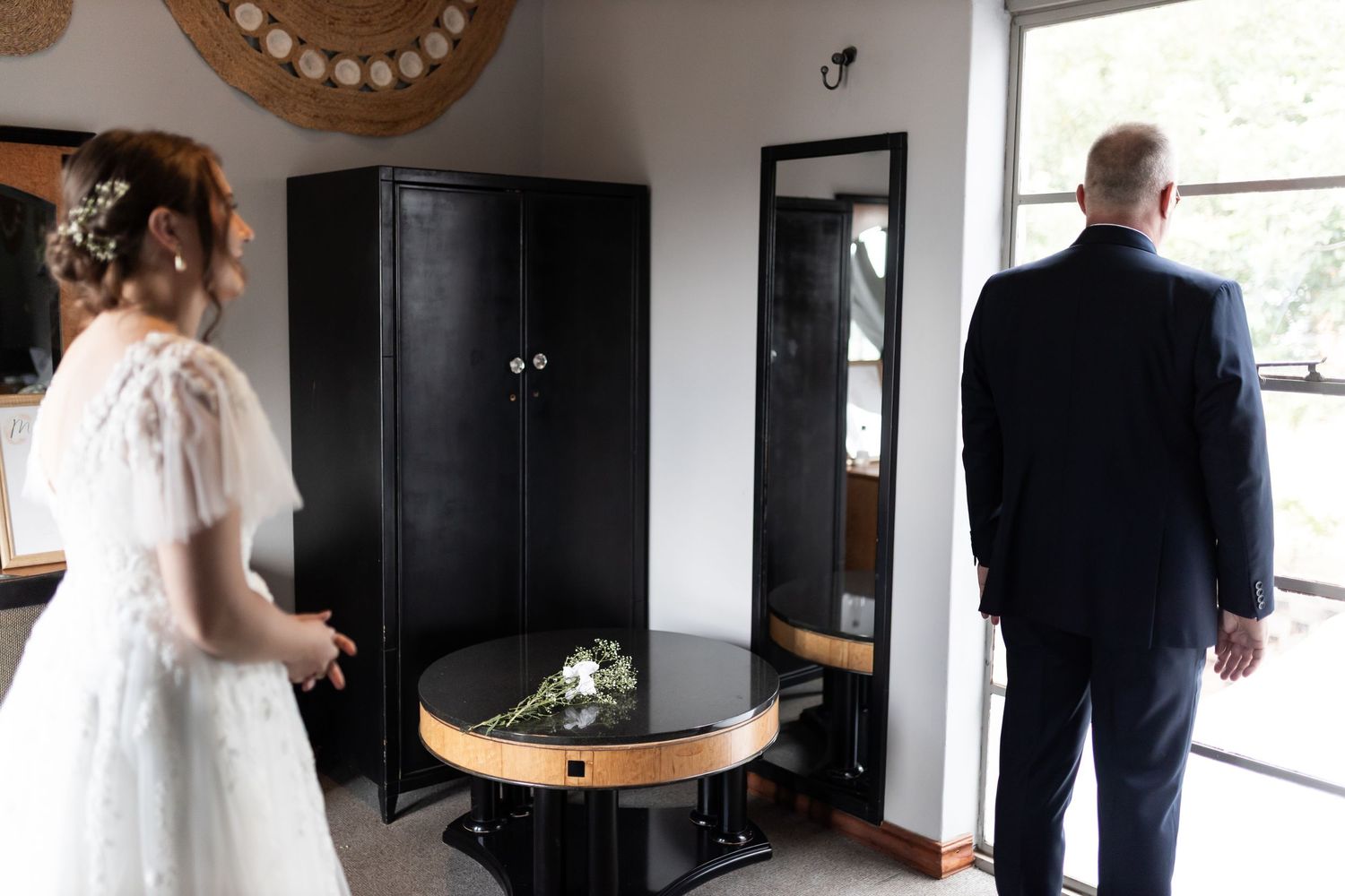 A wedding dress and suit seen from behind in a private first look moment.