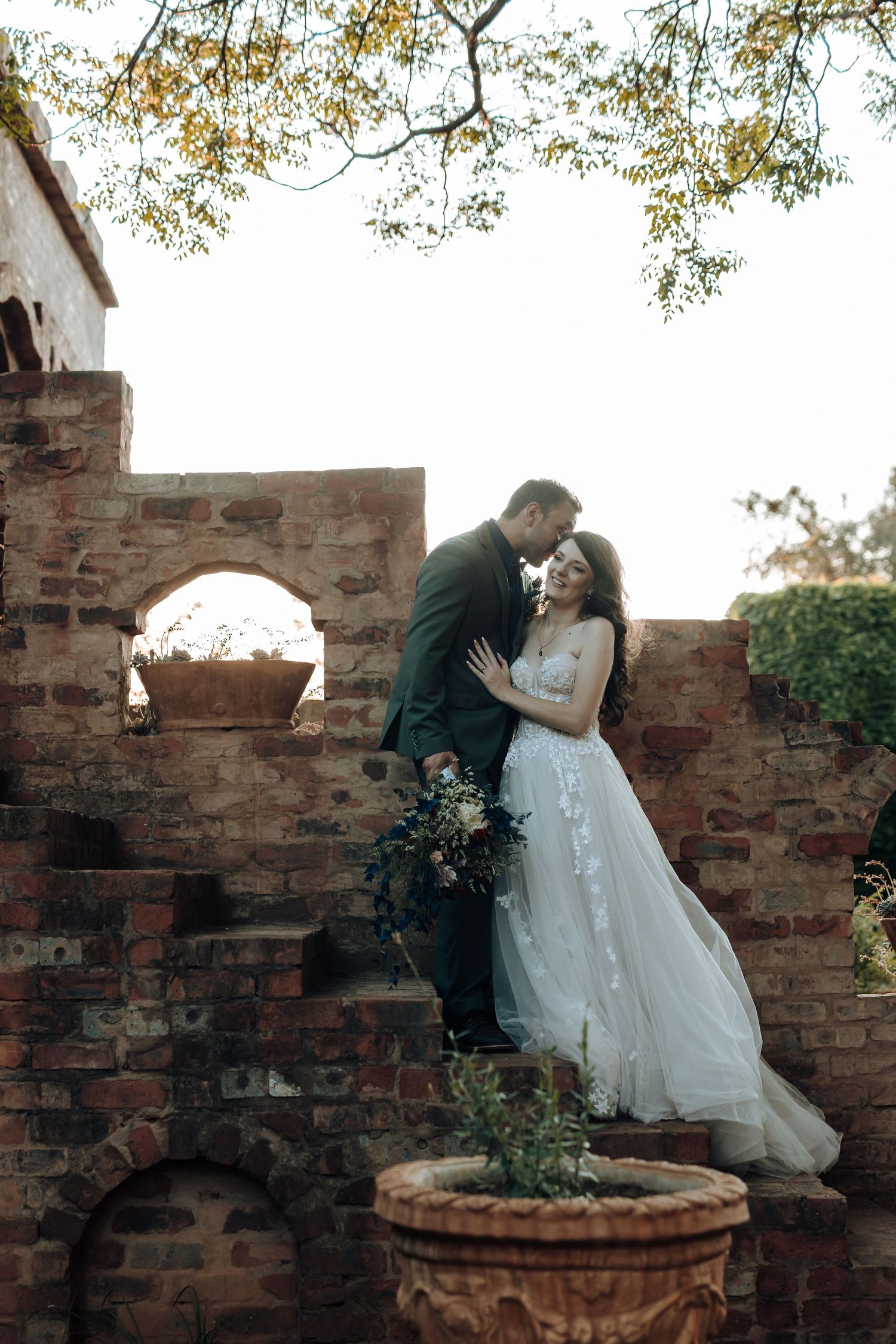 A tender moment captured between newlyweds on vintage brick architecture with arched details.