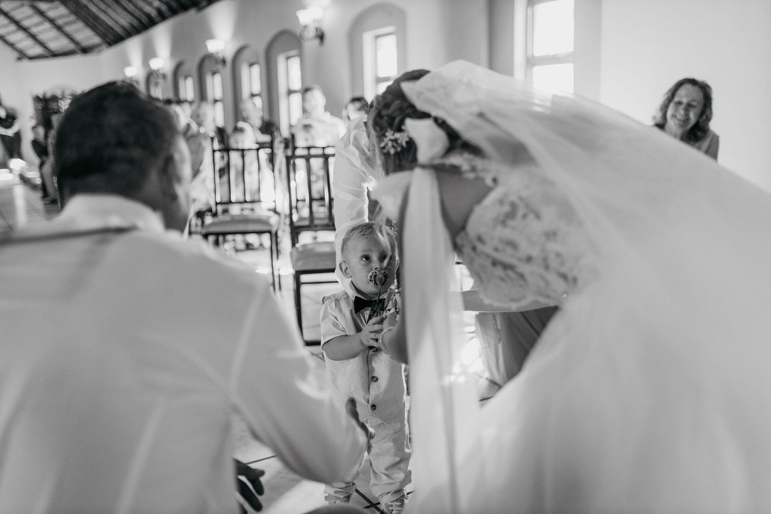 Black and white photo of child participating in wedding ceremony inside rustic venue.