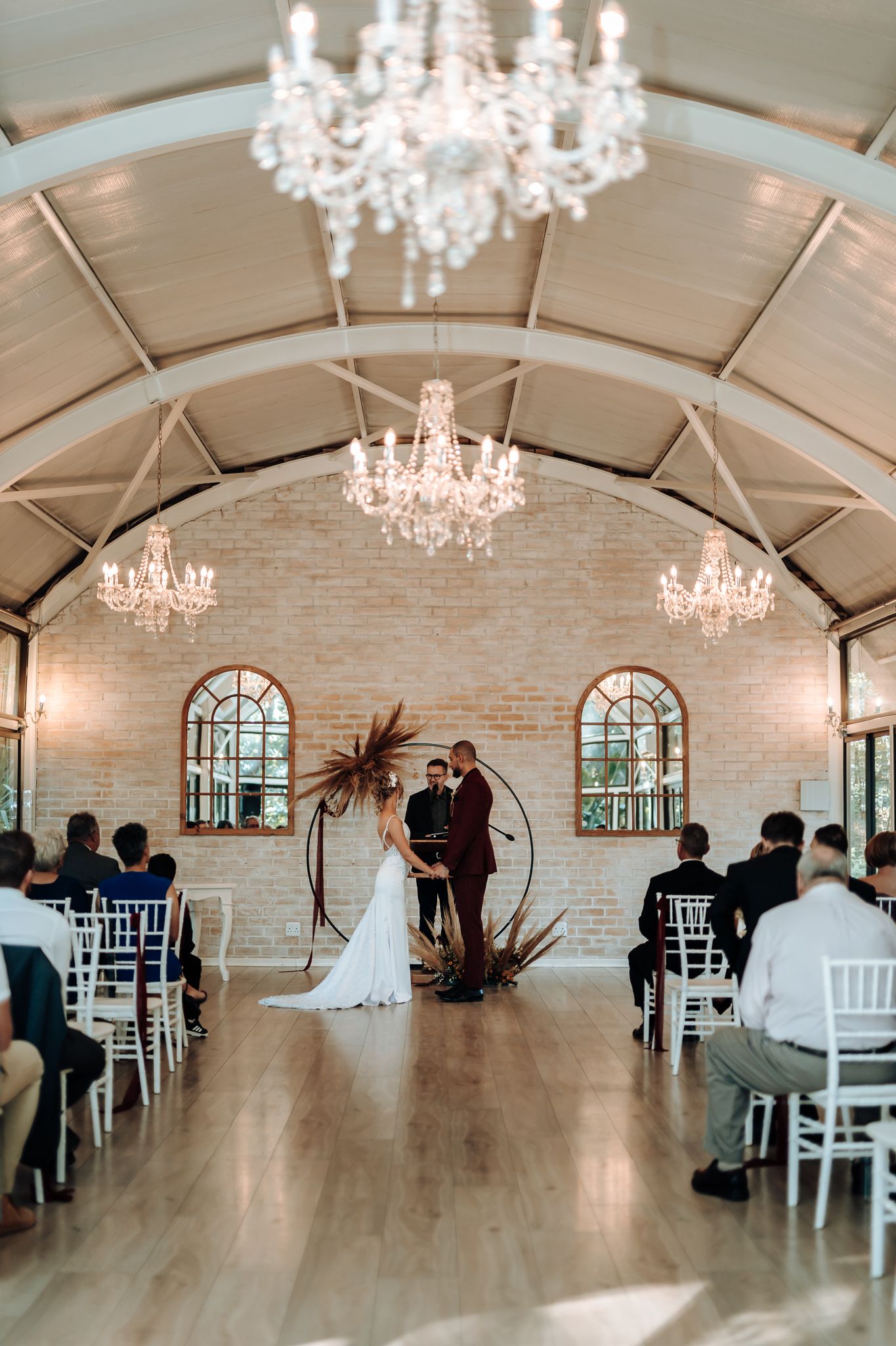 Beautiful wedding ceremony in a light-filled chapel with crystal chandeliers and exposed brick walls.