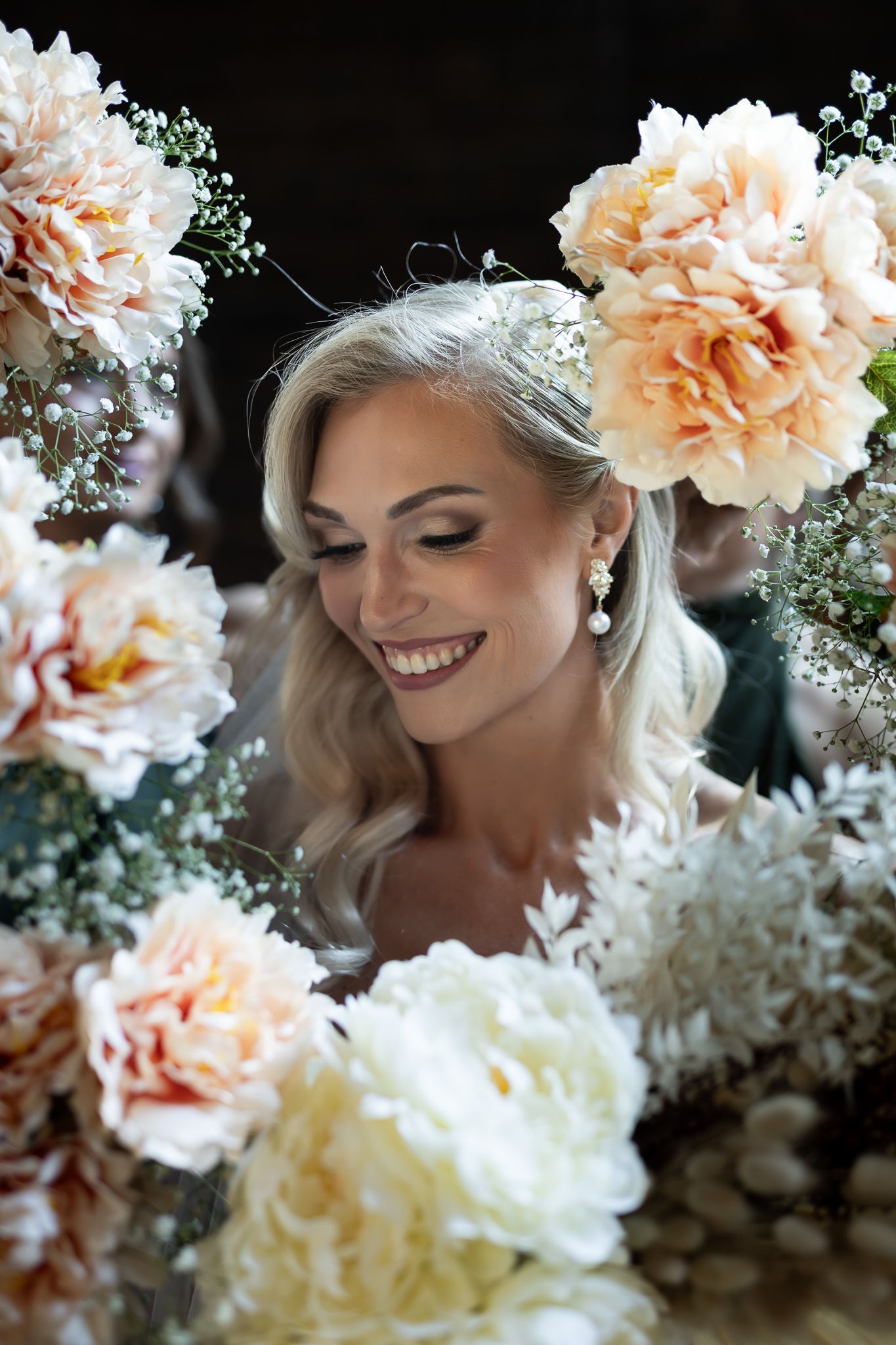Romantic bridal portrait surrounded by soft peach and white peonies with delicate baby's breath accents.