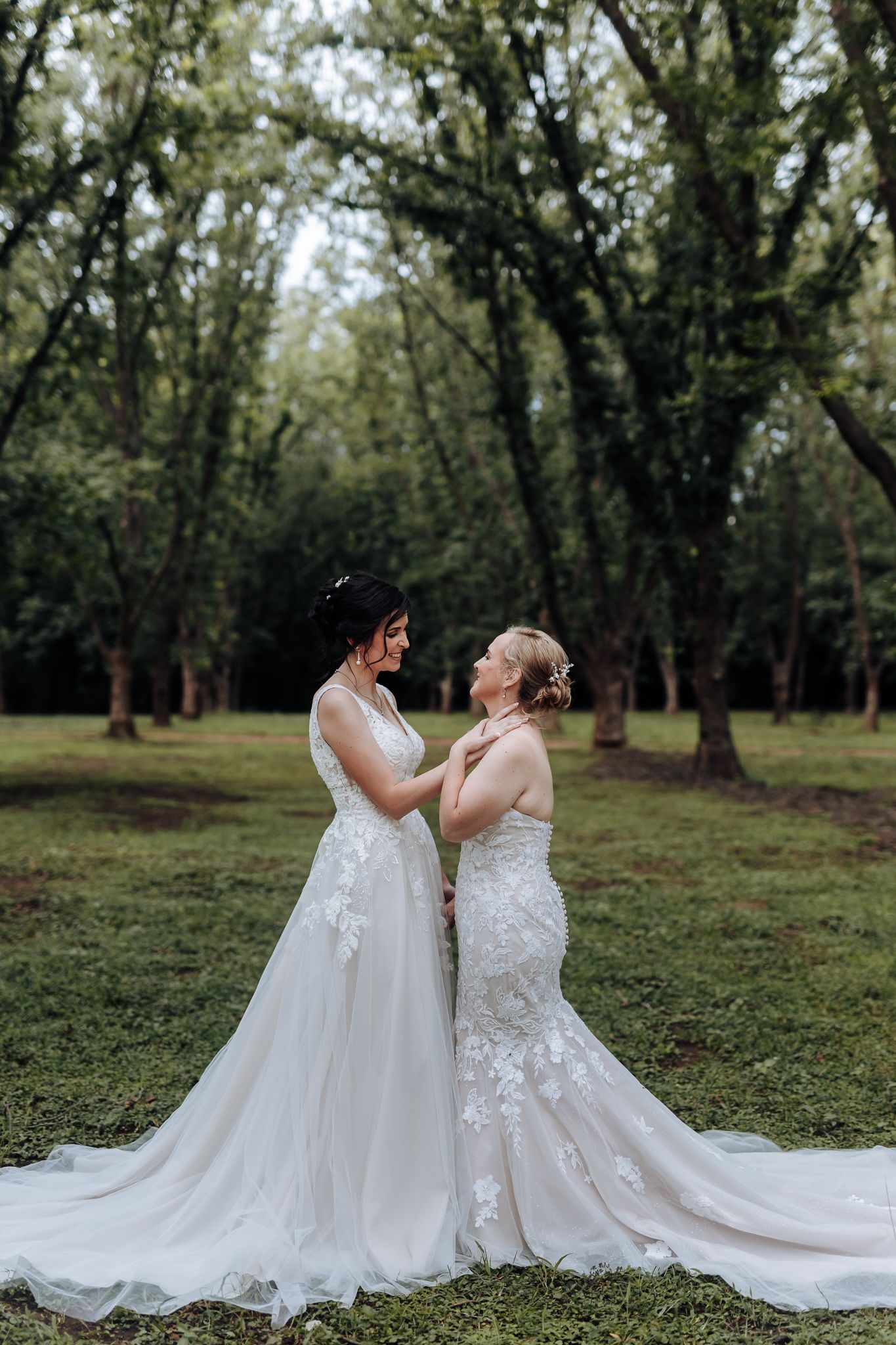 Two elegant wedding dresses photographed in a serene wooded setting.
