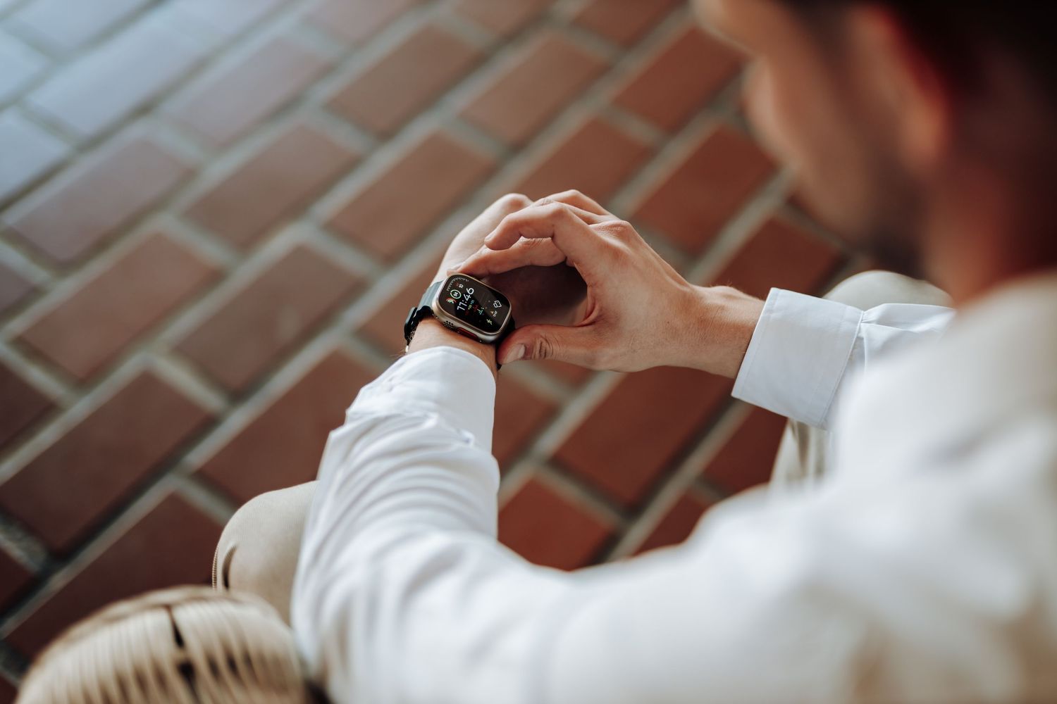 Close-up view of hands checking a smartwatch while seated in an elegant setting.