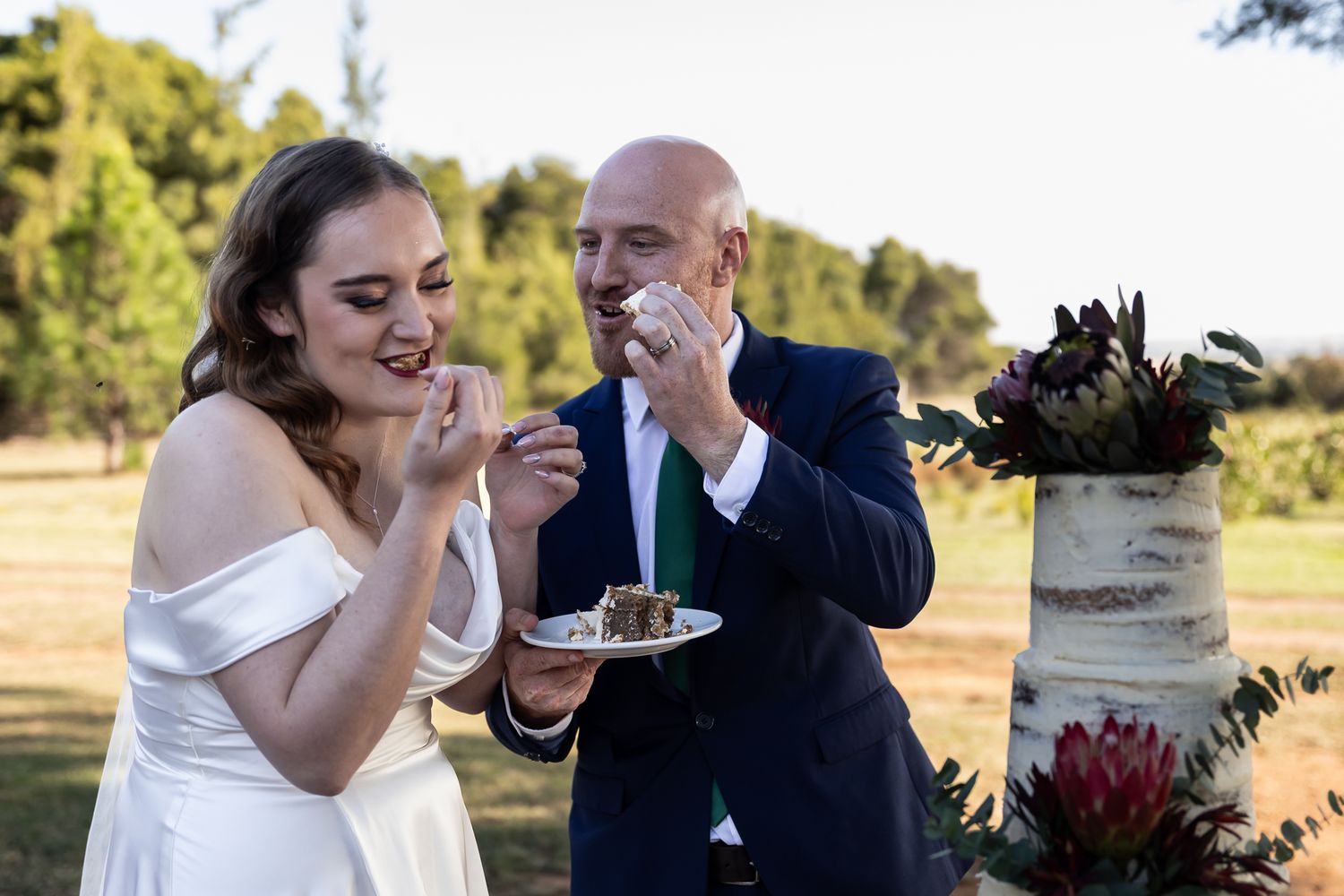 Wedding couple enjoying desserts together at their outdoor celebration.