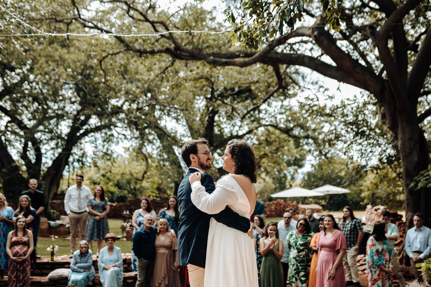 First dance at outdoor wedding reception with guests watching from chairs.