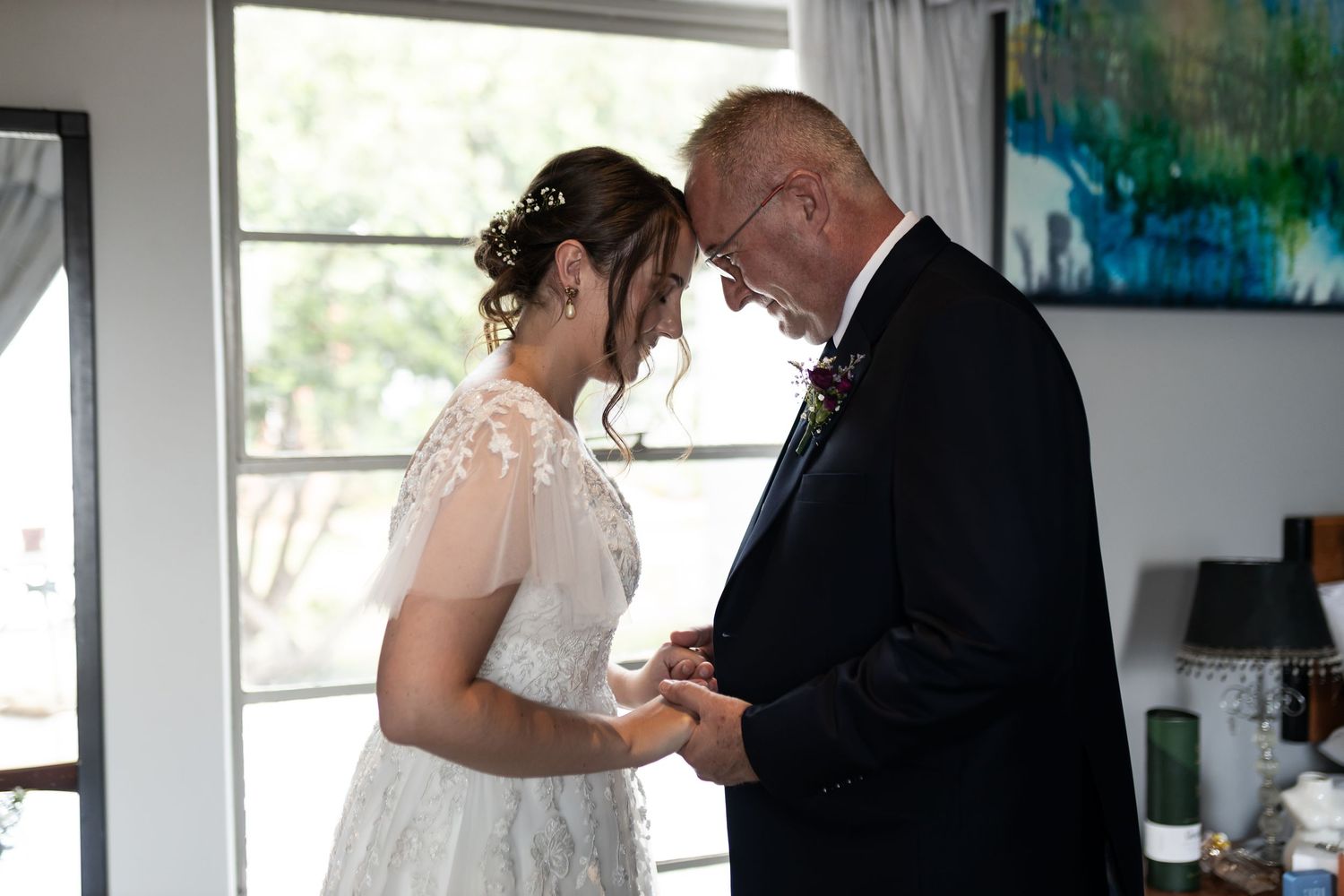 An intimate moment captured during a wedding ceremony in a bright interior space with modern art.