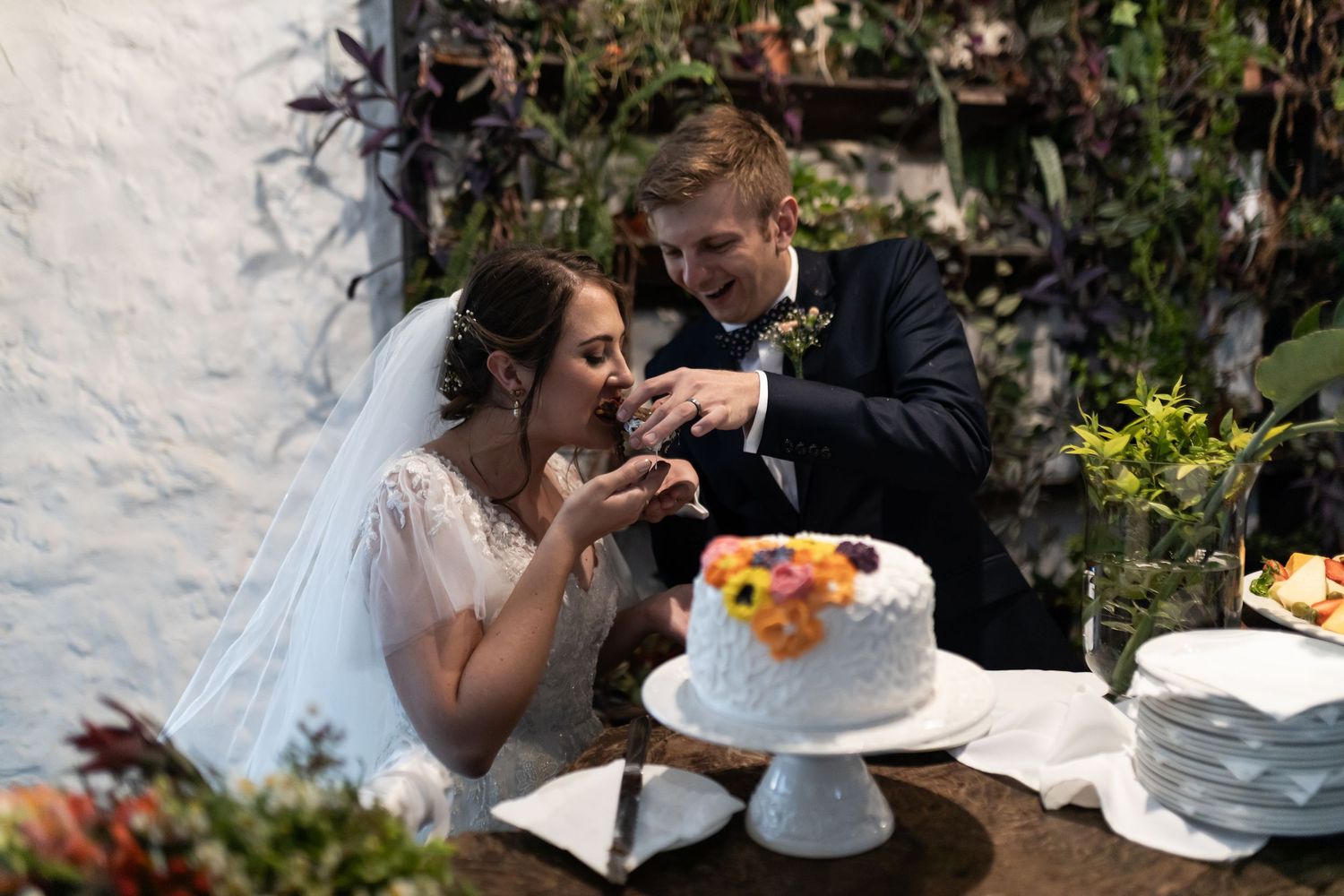 Wedding couple sharing their first bite of cake during traditional cake cutting ceremony.