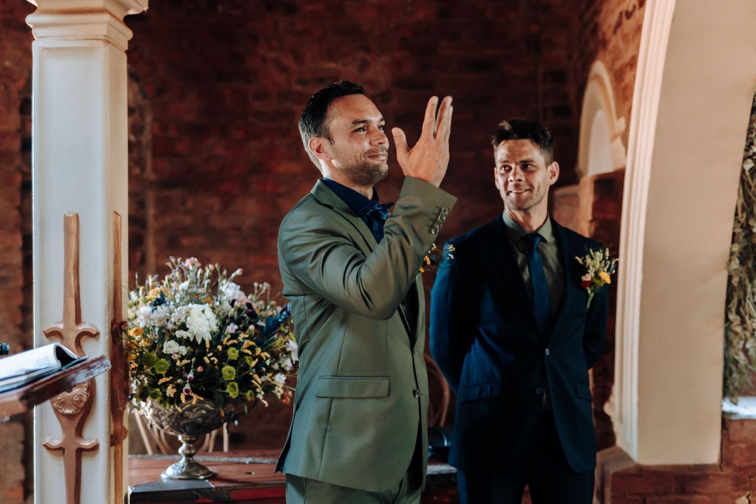 Wedding guest wiping tears while standing next to another guest during emotional ceremony.