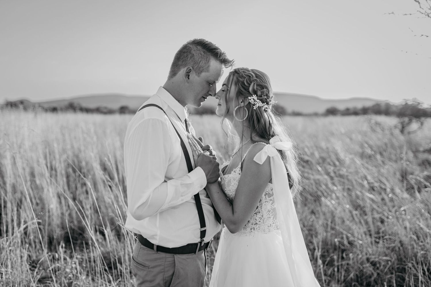 Black and white portrait of romantic wedding couple in natural field setting.