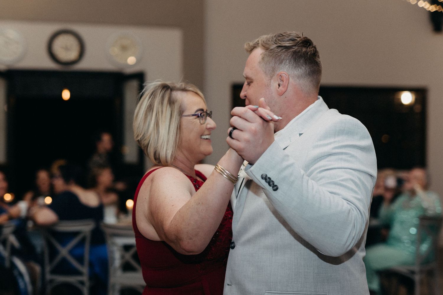 A couple shares an intimate moment while slow dancing at an indoor reception venue.