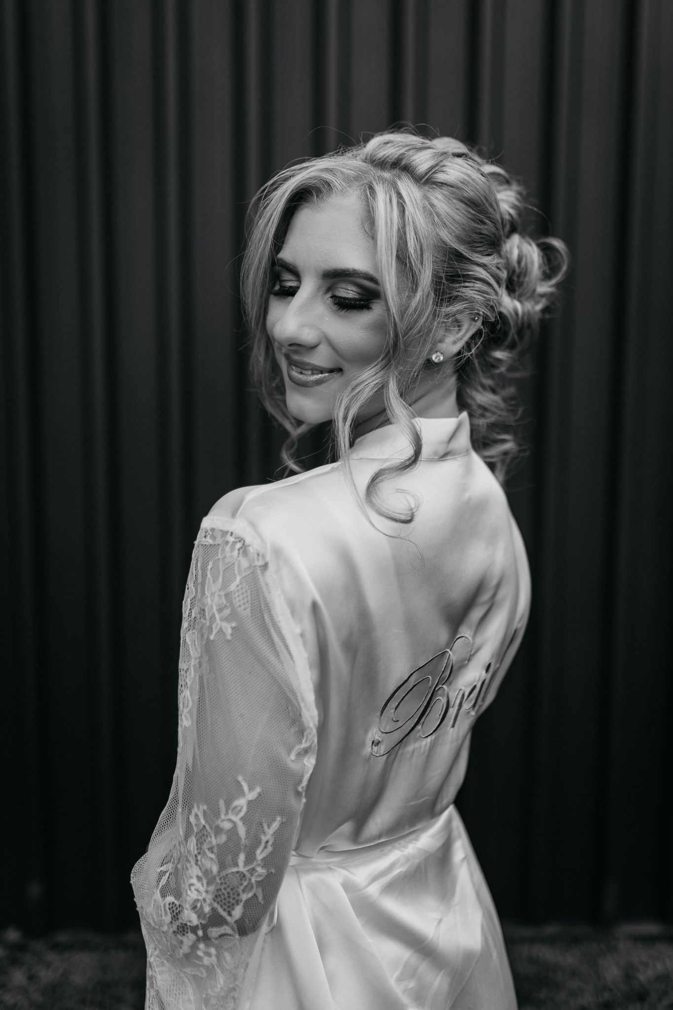 Black and white photo of an updo hairstyle and white lace bridal robe.