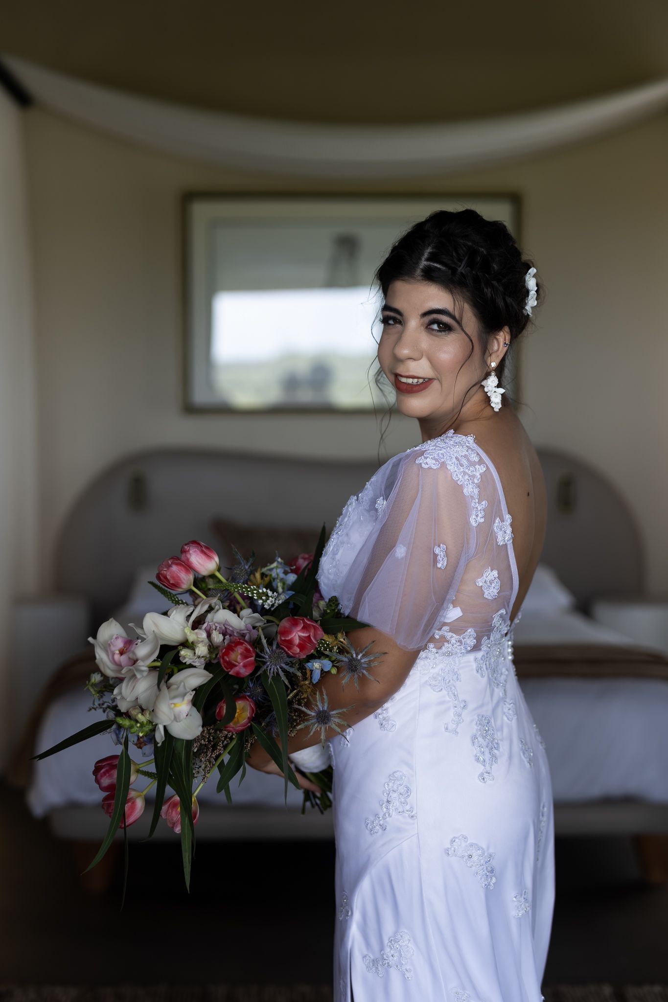 A side view of someone in a wedding dress holding a colorful floral bouquet.