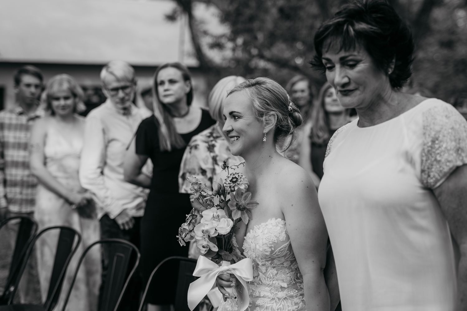 Black and white photo of a wedding ceremony celebration with guests in an outdoor setting.
