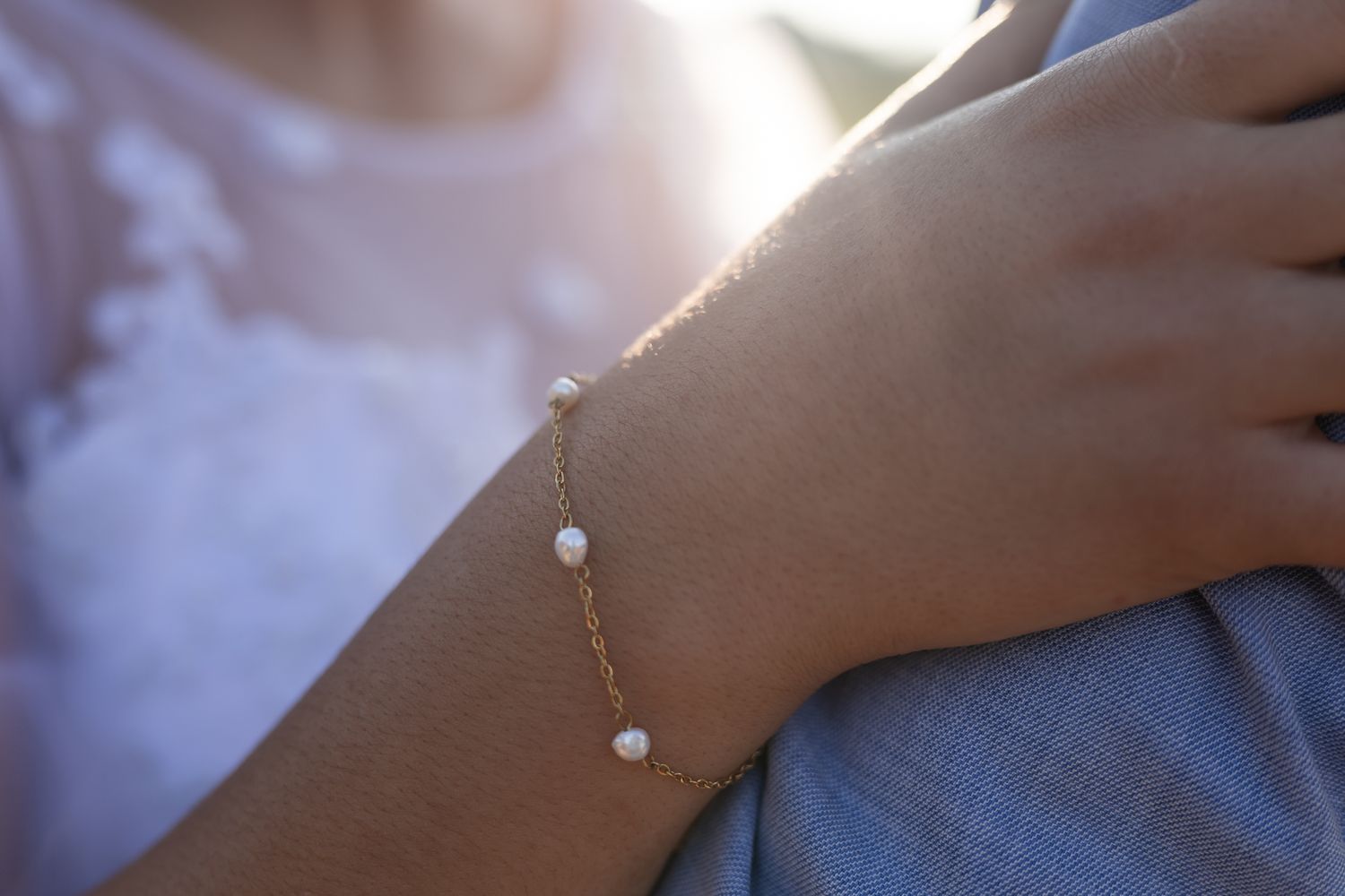Delicate pearl bracelet detail shot against white wedding dress.