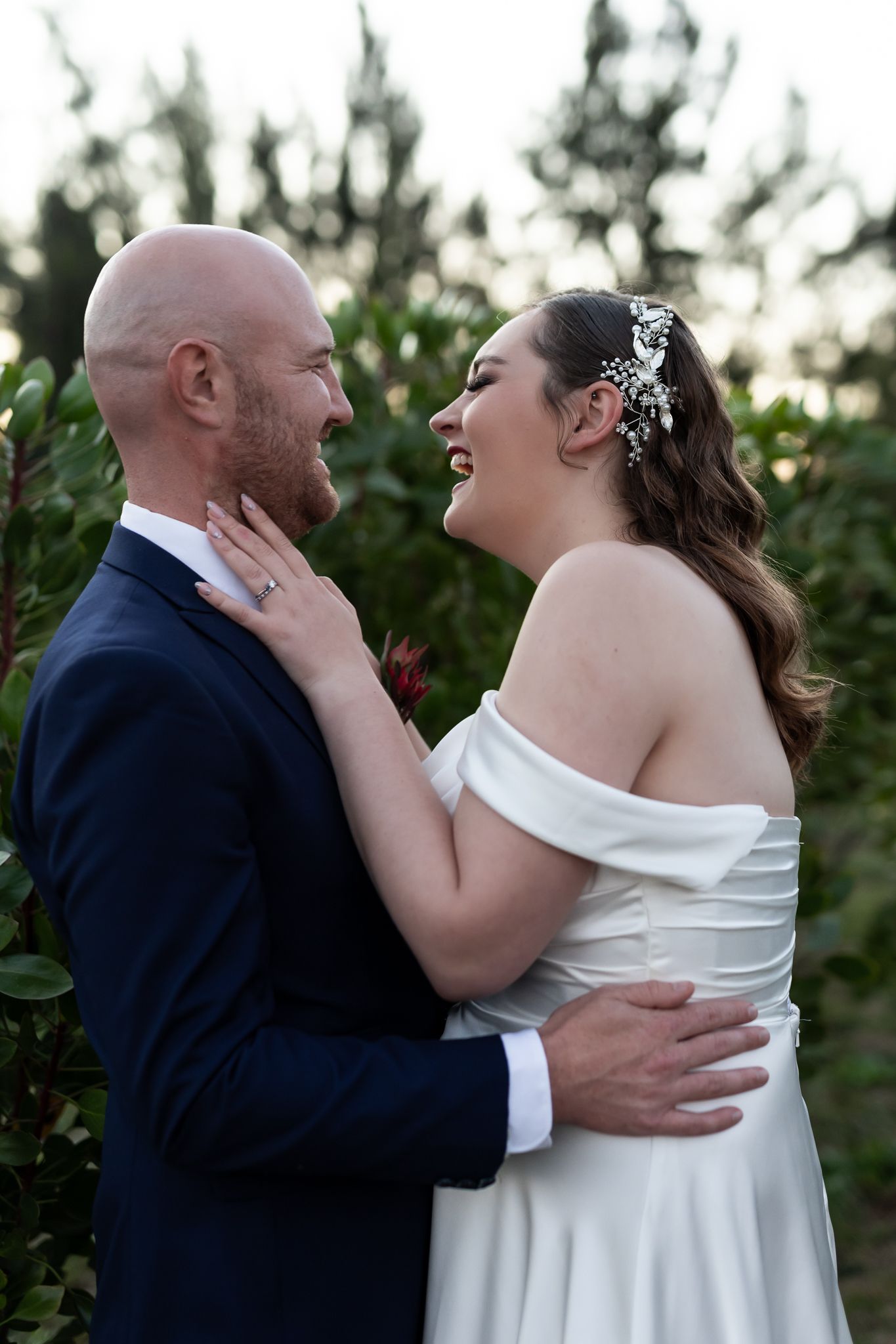 A joyful candid moment shared between newlyweds in an outdoor garden setting.