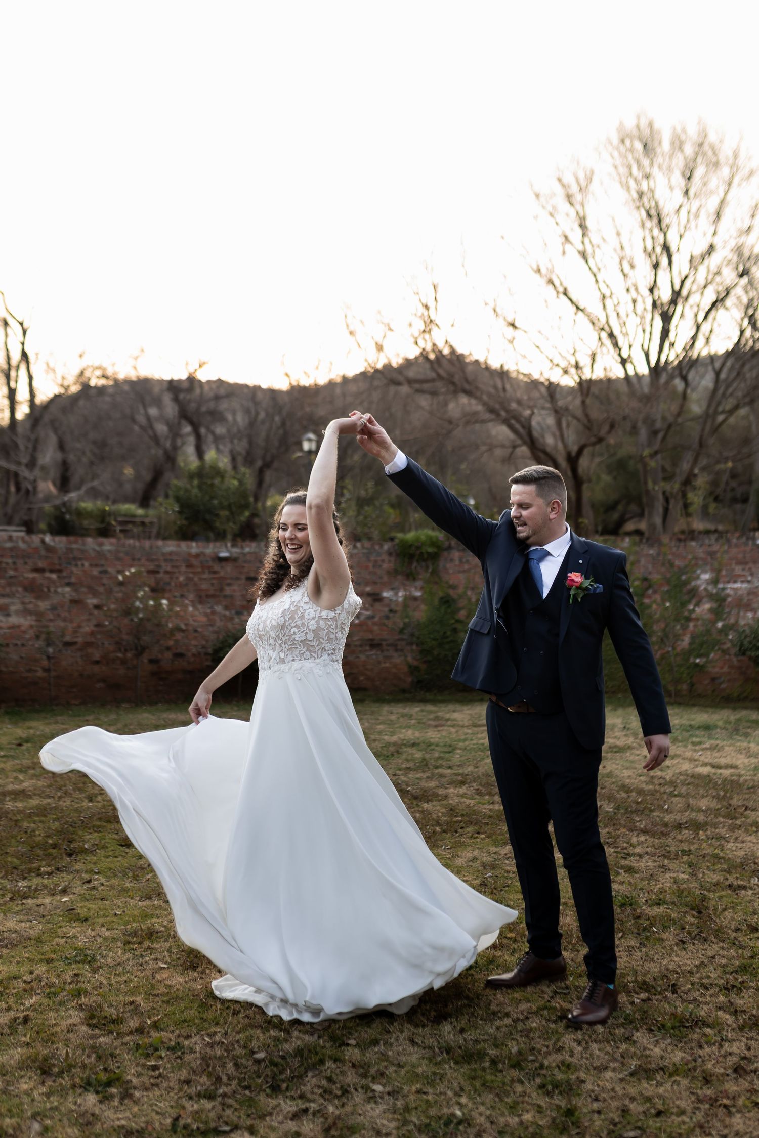 A bride spins and twirls in her flowing white wedding gown while dancing outdoors with her groom in autumn.