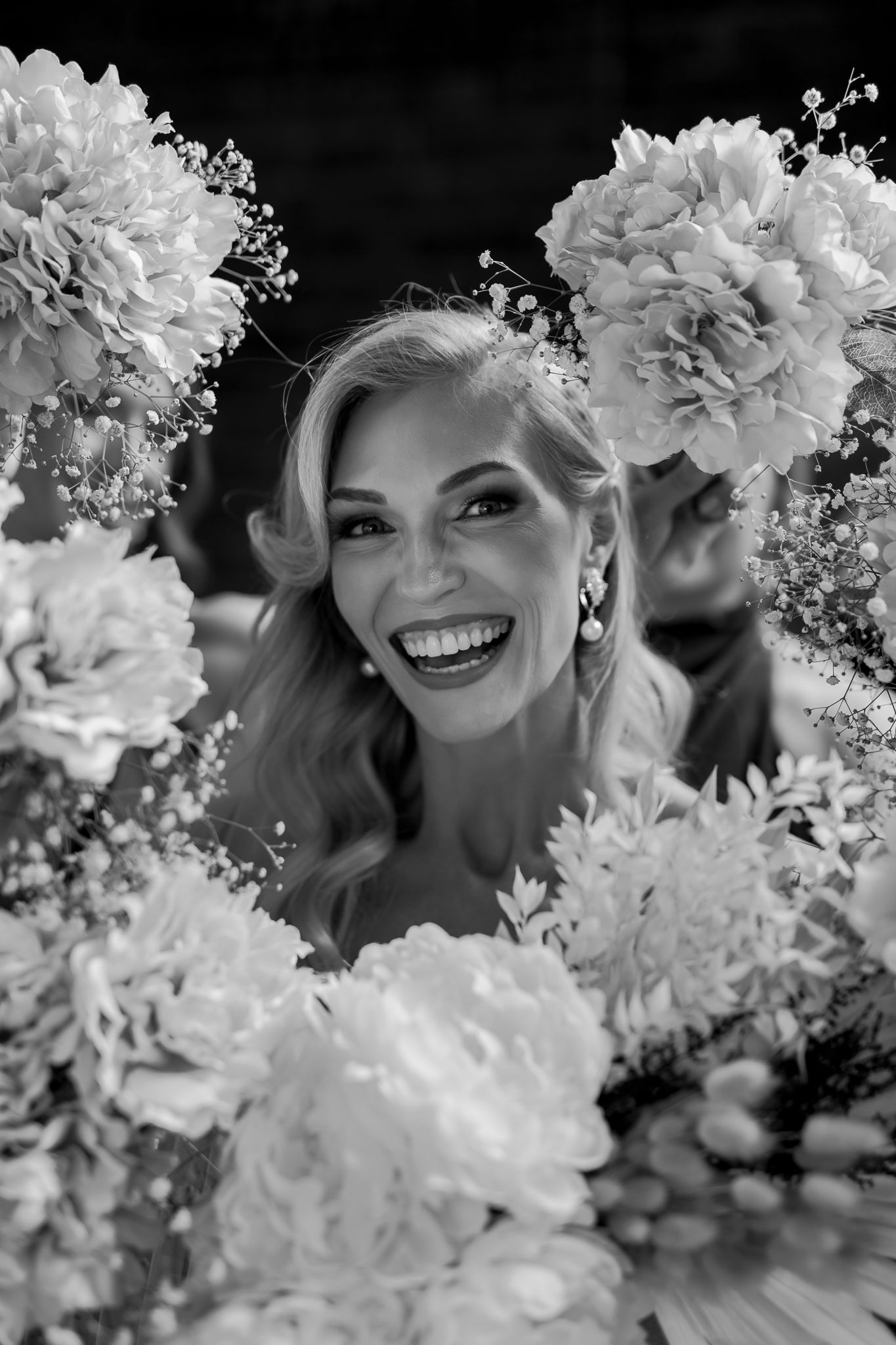 Joyful bridal portrait framed by elegant white peonies and baby's breath in black and white.