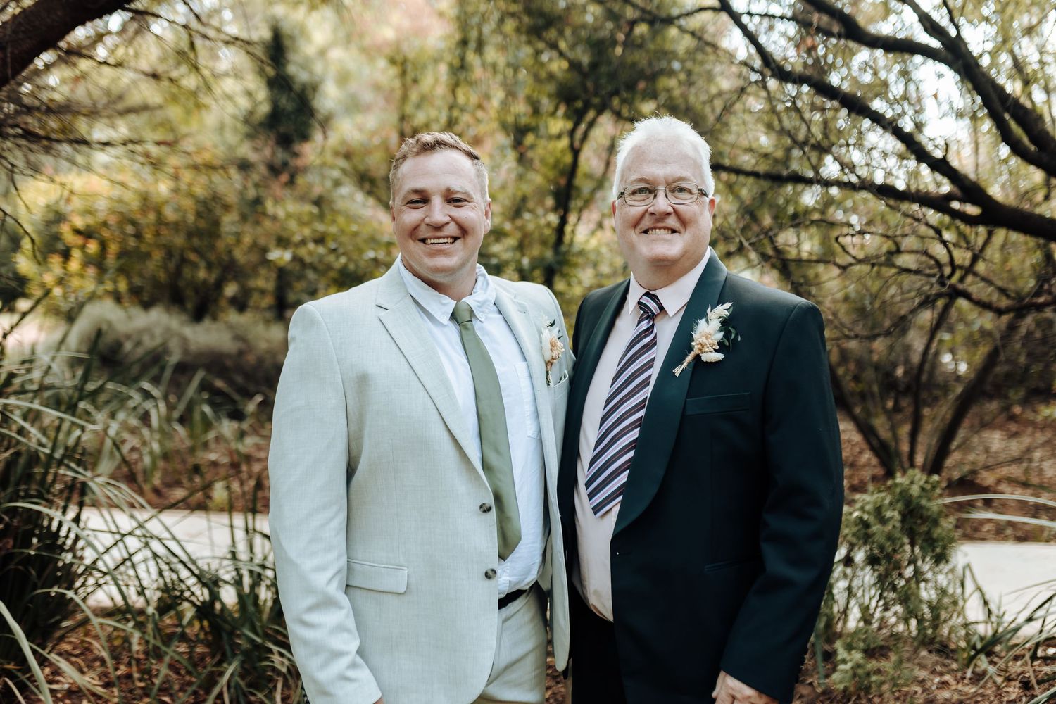 Two people in formal attire pose together outdoors during wedding celebration.