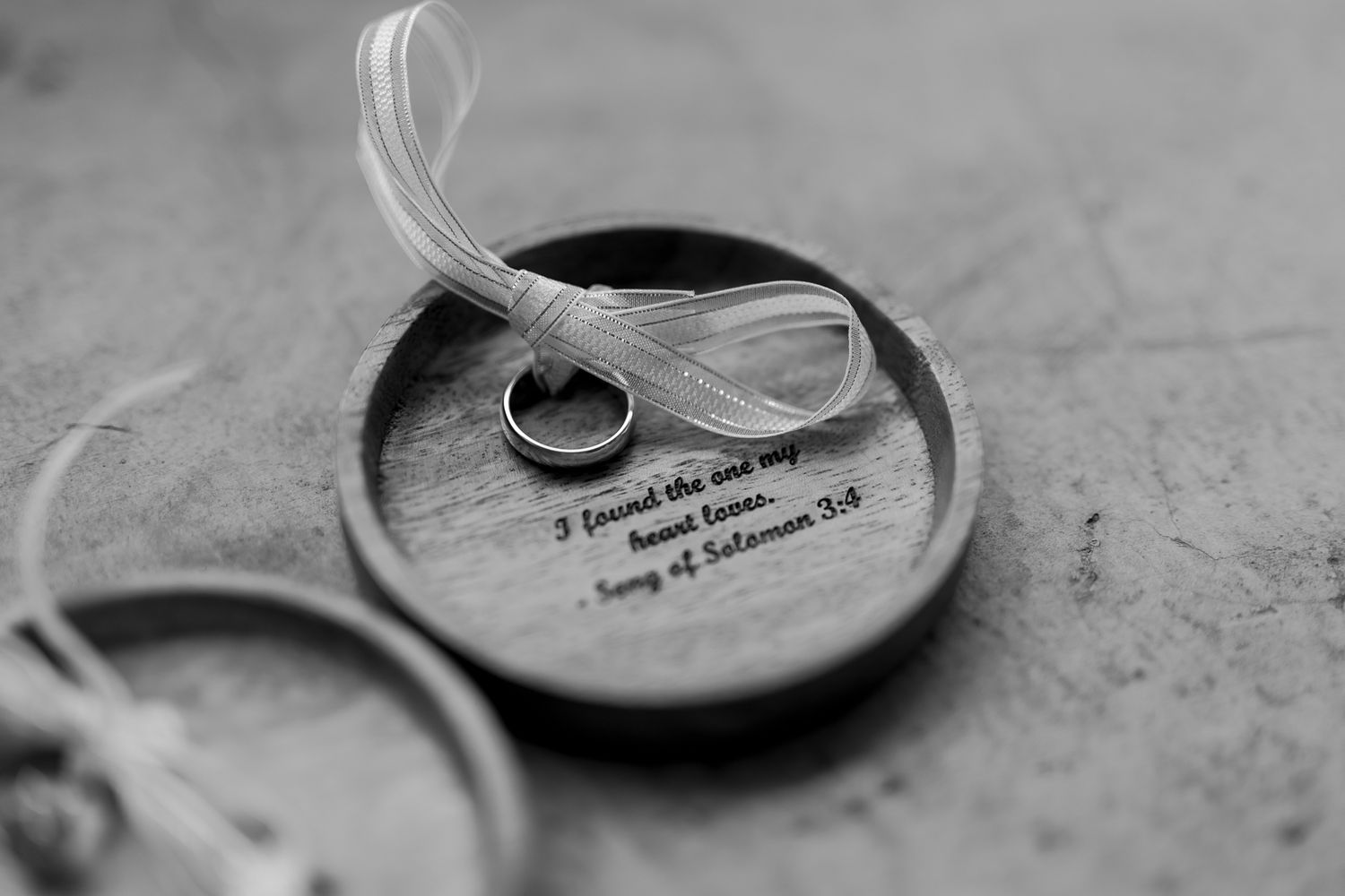 Close-up black and white shot of wedding rings with feather detail.