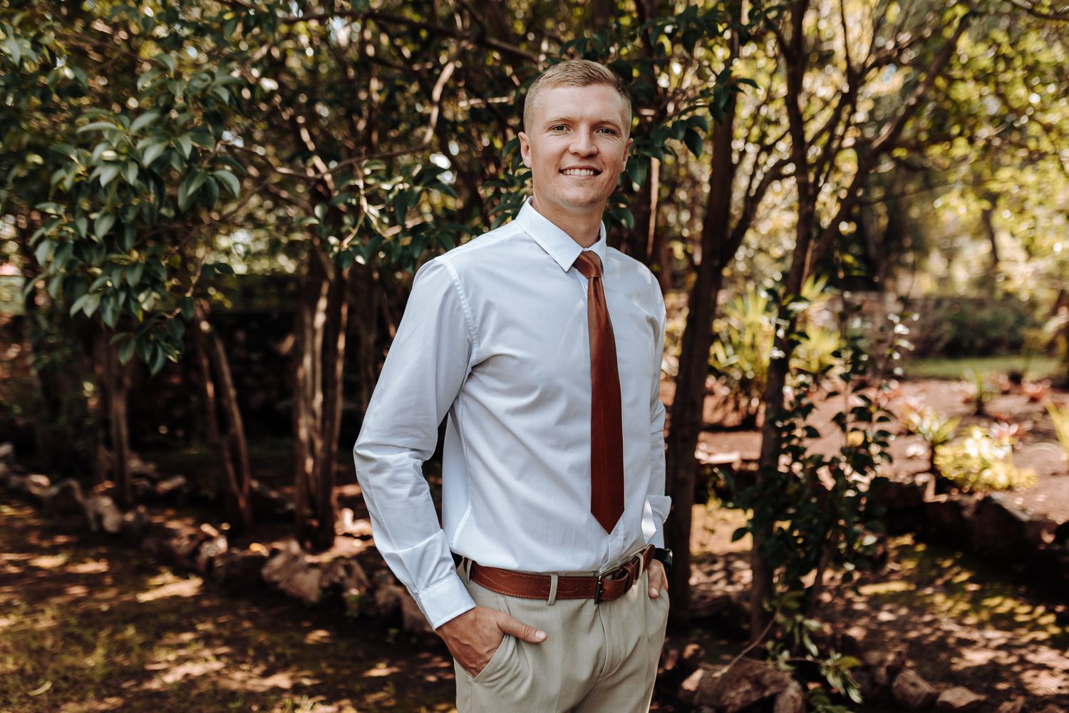 Professional headshot of man in business attire against autumn woodland setting.