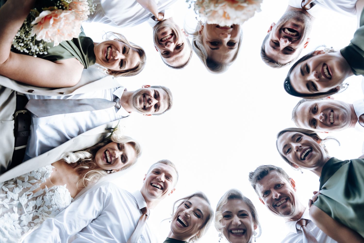 Circle perspective photo of wedding party looking down and smiling at camera.