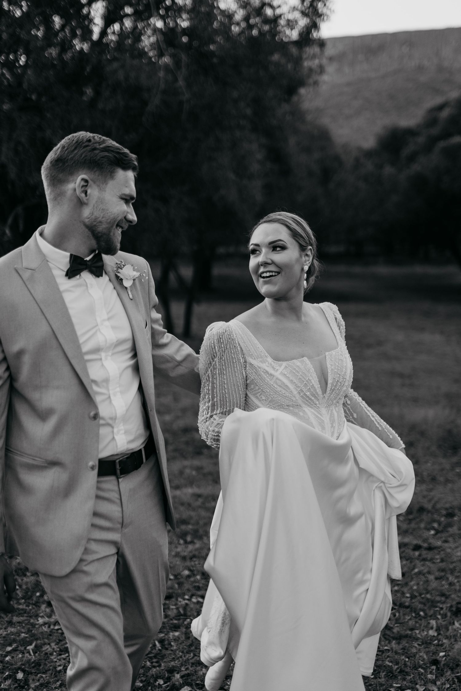 Black and white wedding photo of couple laughing together in formal attire.