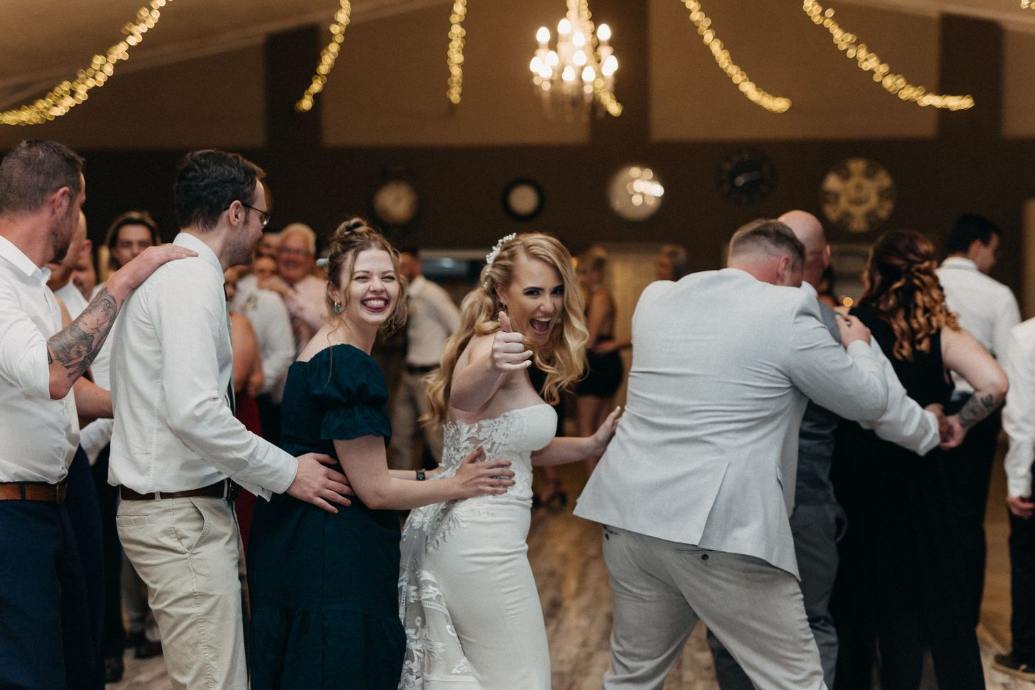 Wedding reception dance floor filled with celebrating guests under elegant chandeliers.