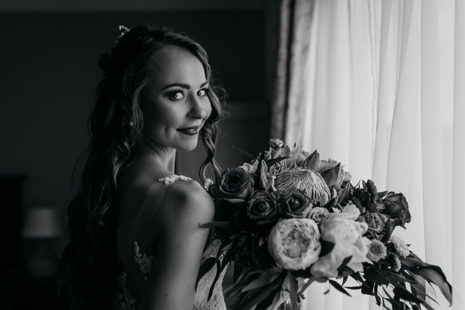 Dramatic black and white portrait of bride with luxurious bouquet.
