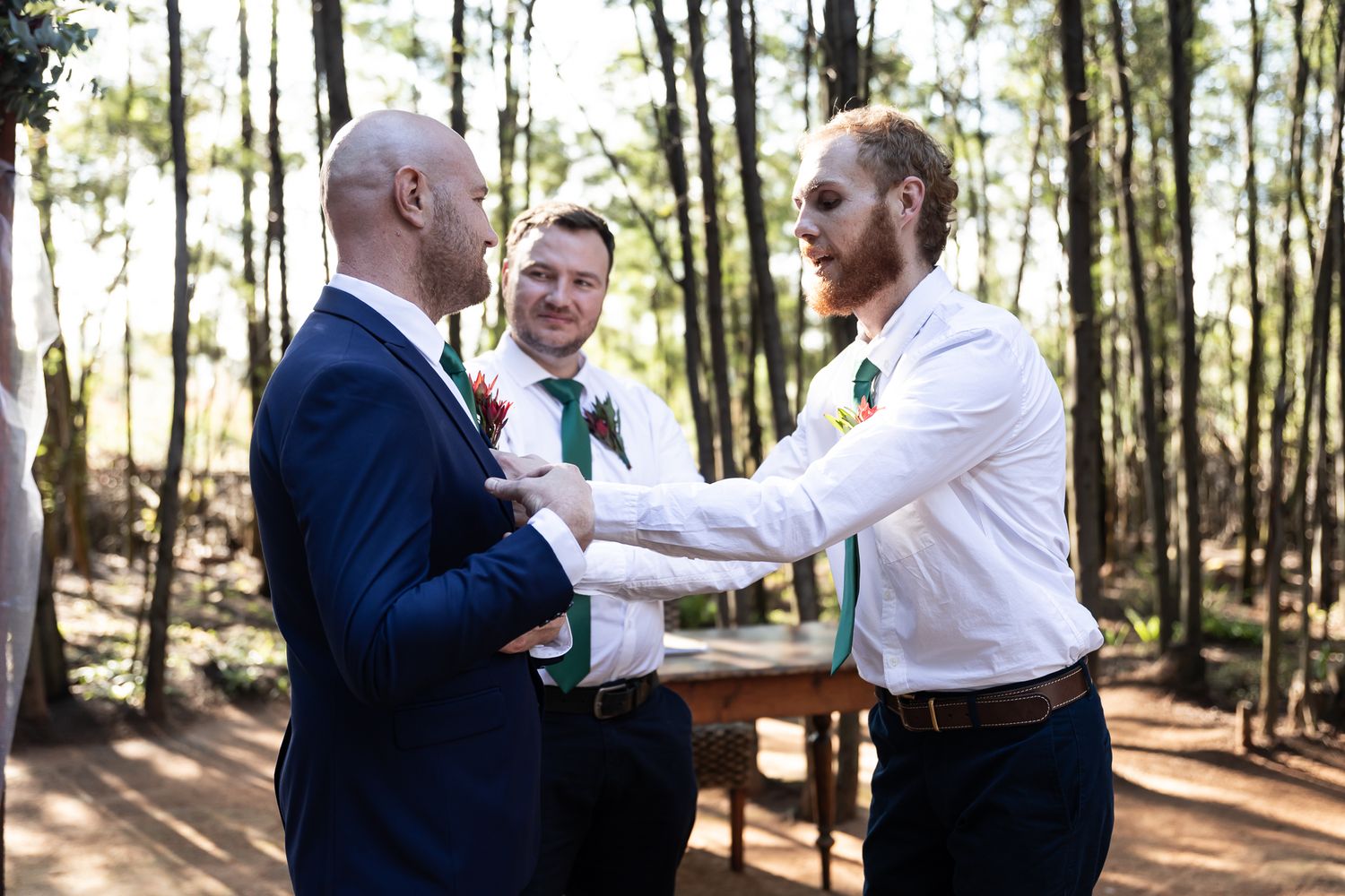 Wedding ceremony in forest setting with guests exchanging vows under trees.