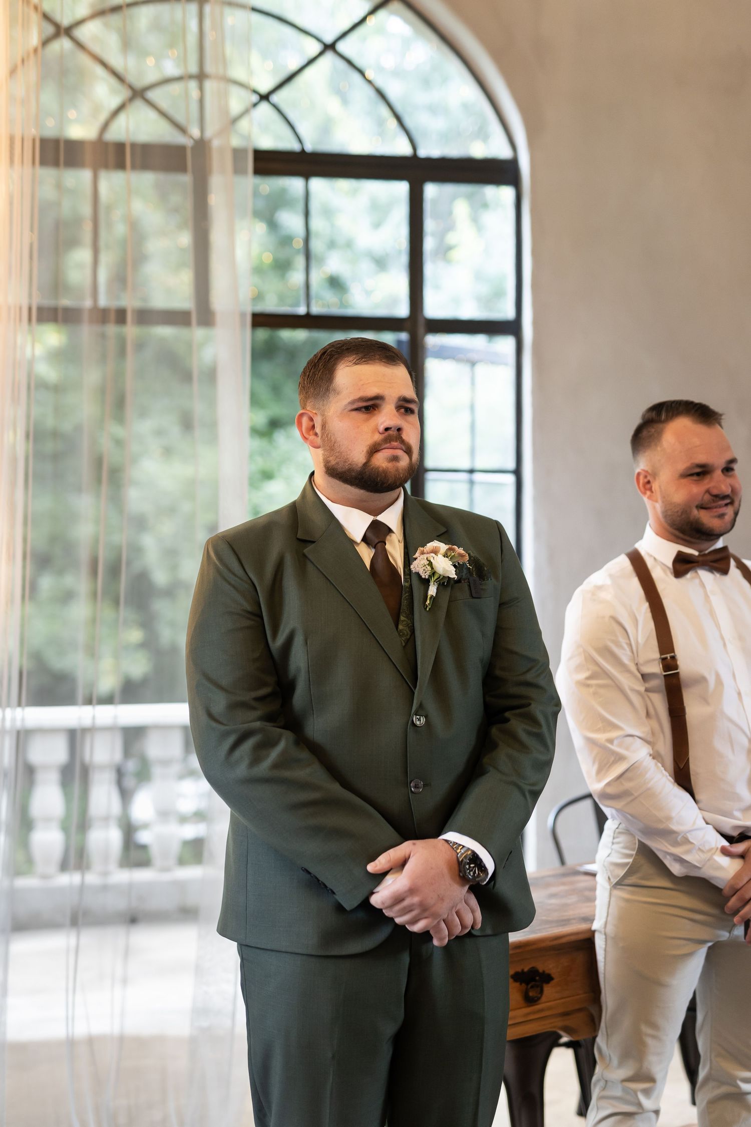 Formal wedding ceremony setting with elegant arched windows and interior architectural details.