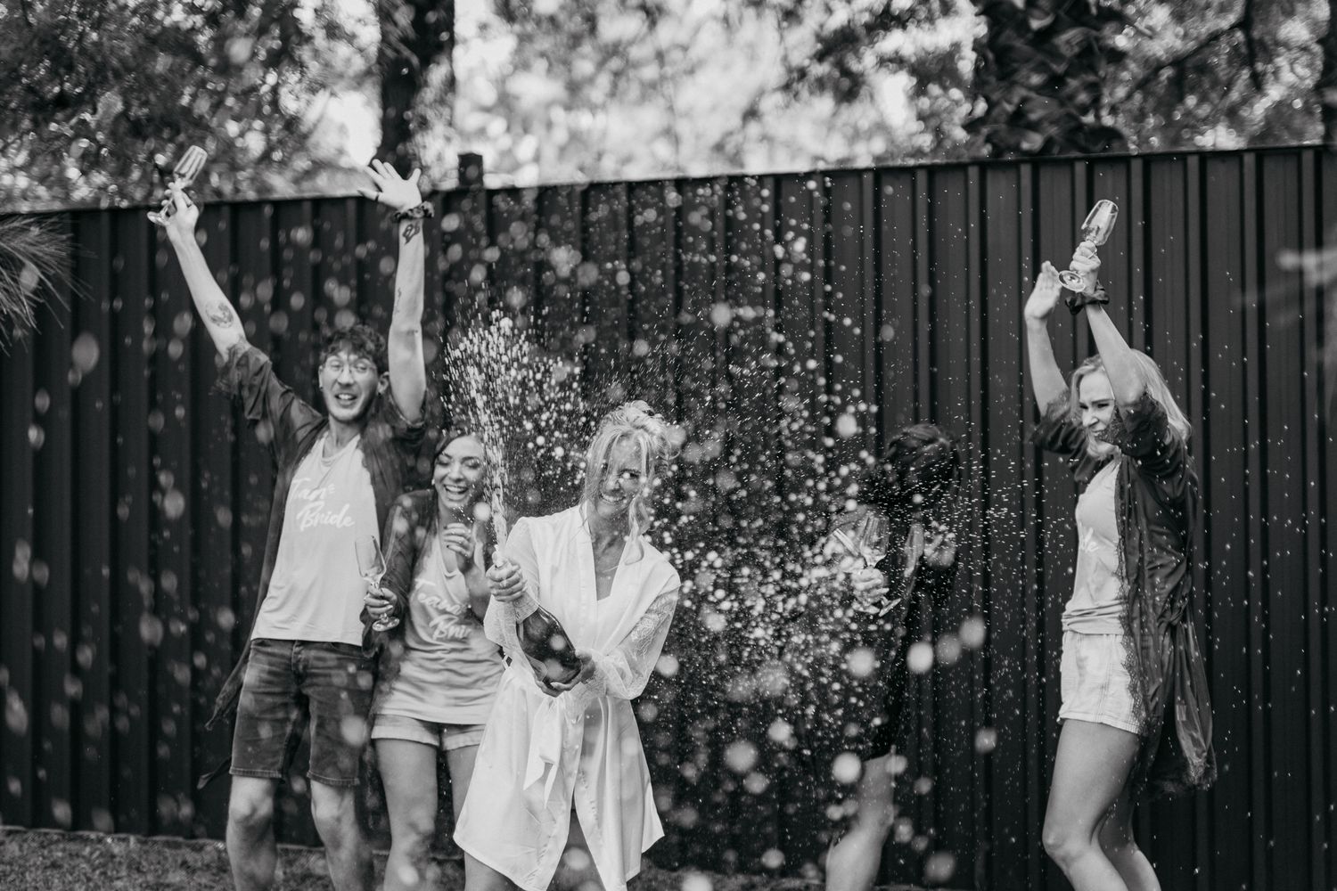 Black and white photo of group jumping and celebrating with water spray.