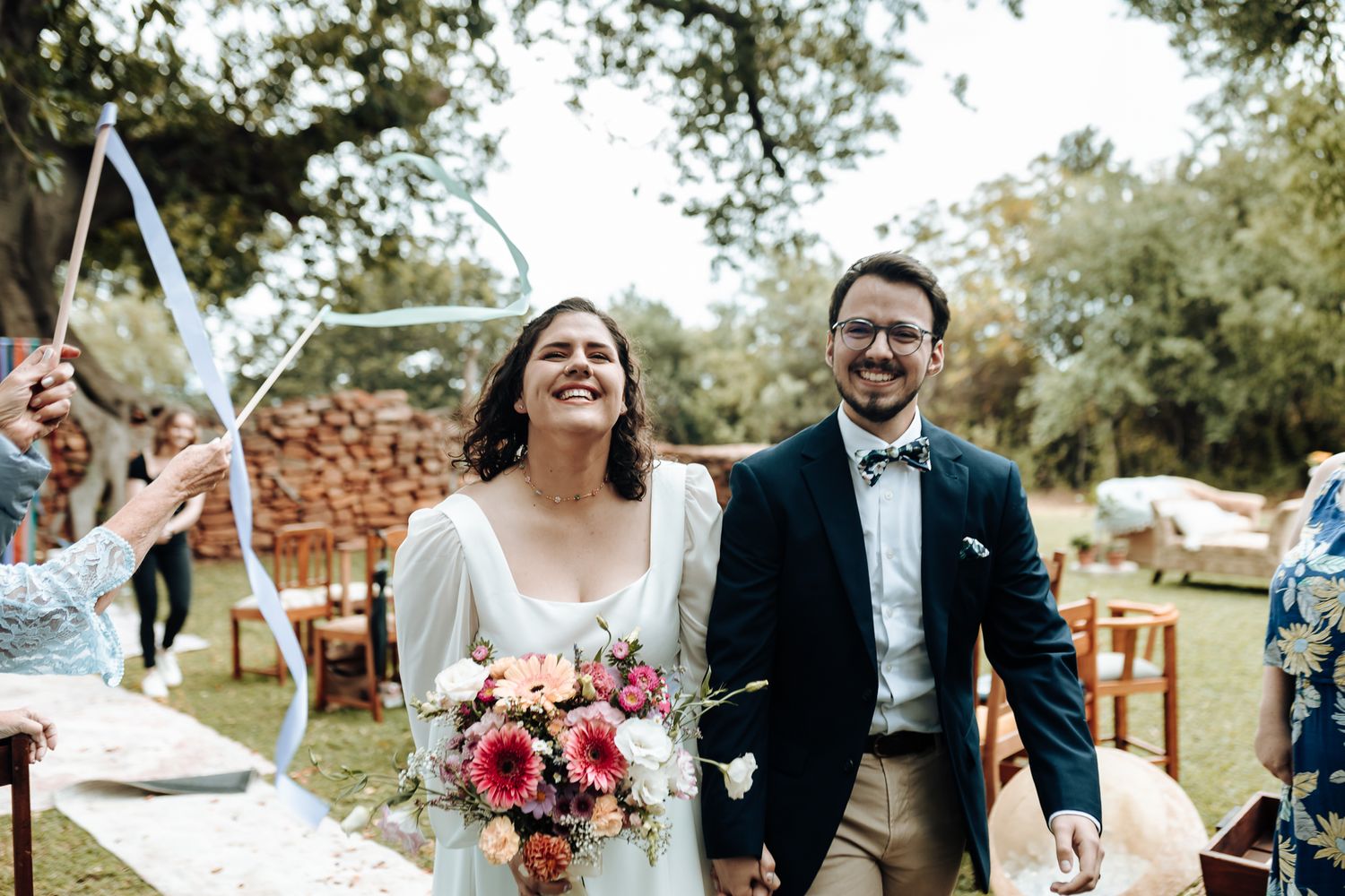 Newlyweds walk down the aisle together at their outdoor garden wedding celebration.