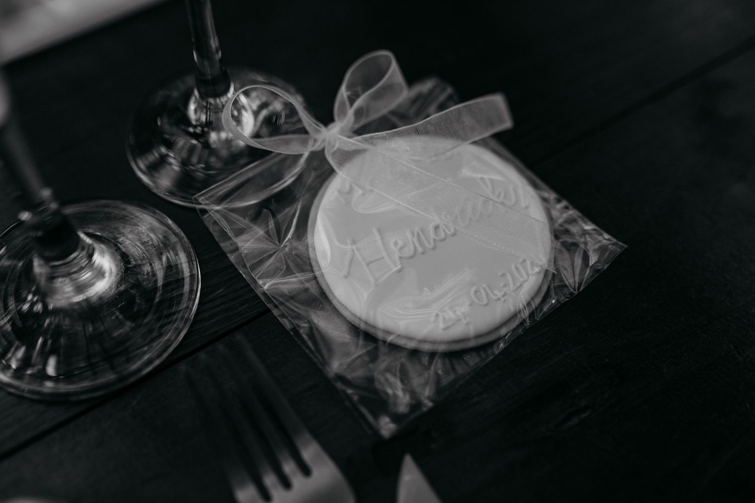 Black and white close-up of an elegantly wrapped wedding favor with ribbon.