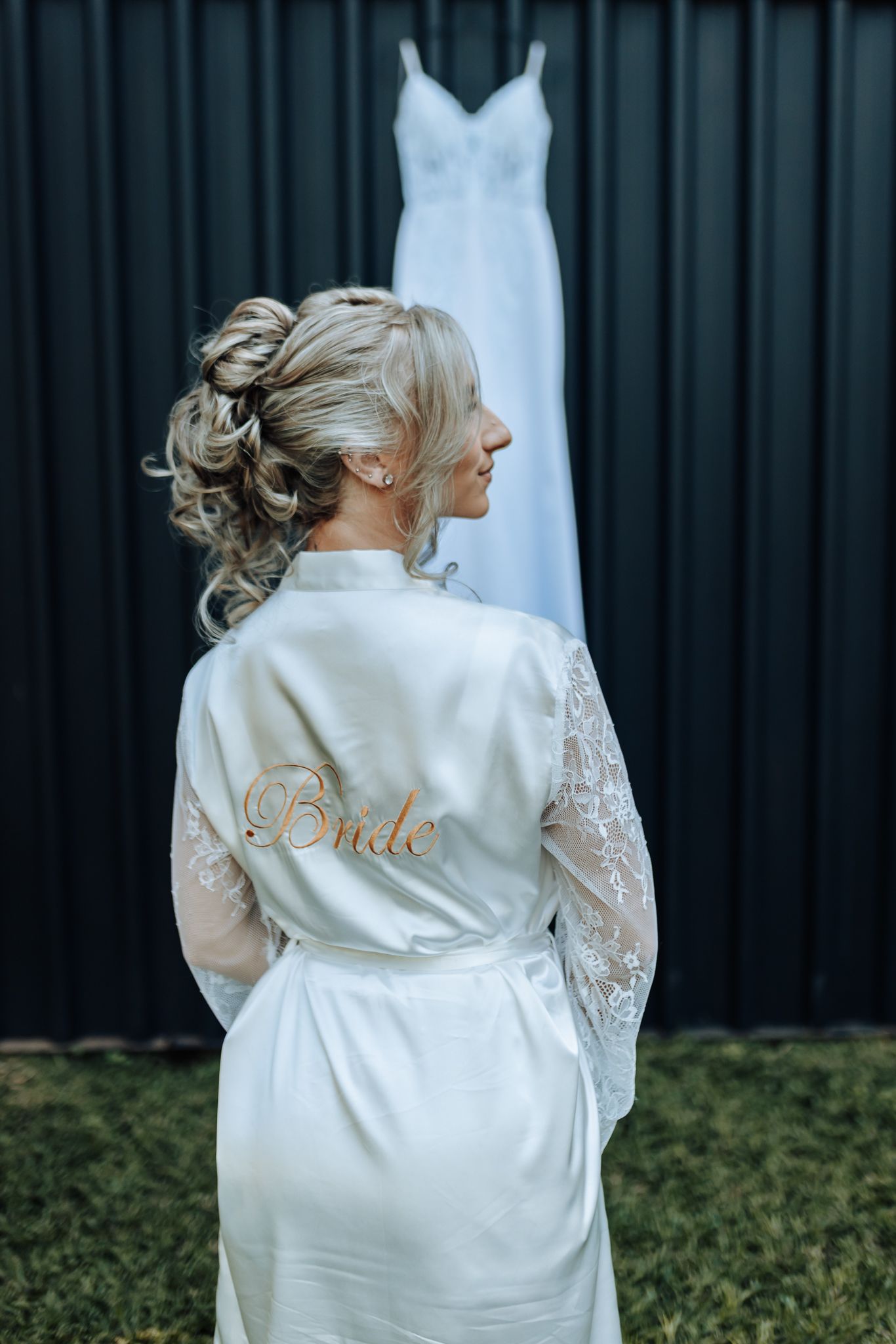White satin bridal robe with lace sleeves and gold 'Bride' embroidery shown from behind.